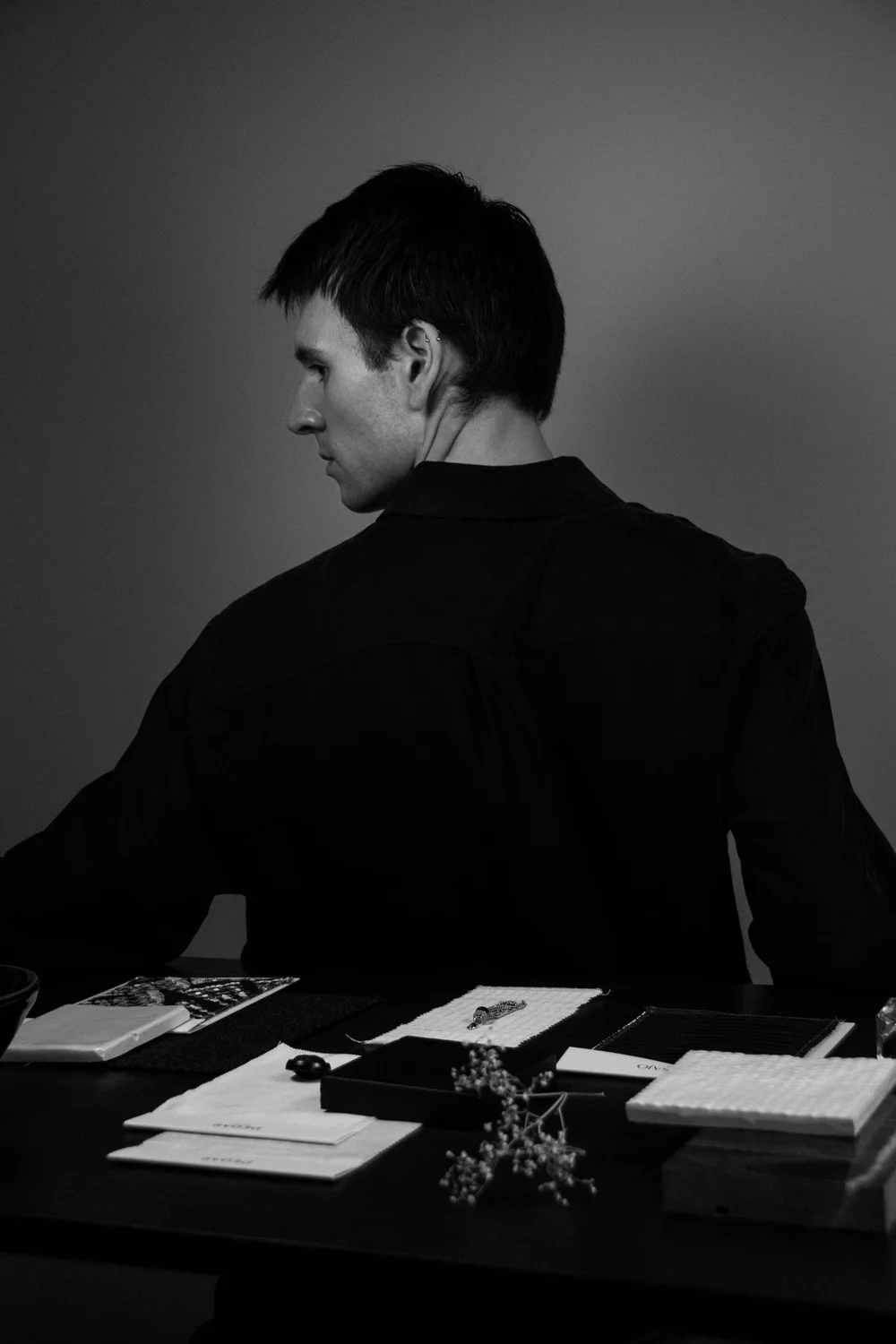 Joost Laméris, founder of Studio Cér, in profile at a table reviewing material and textile samples.