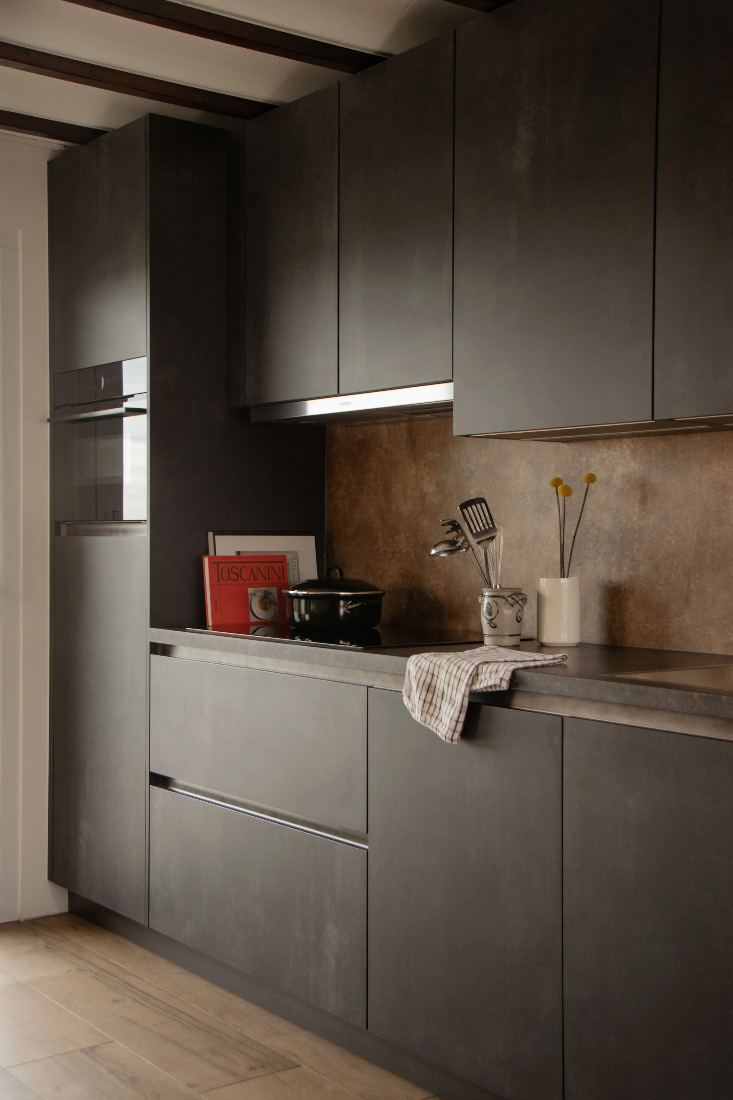 Full view of dark-toned kitchen with integrated cabinetry and warm finishes