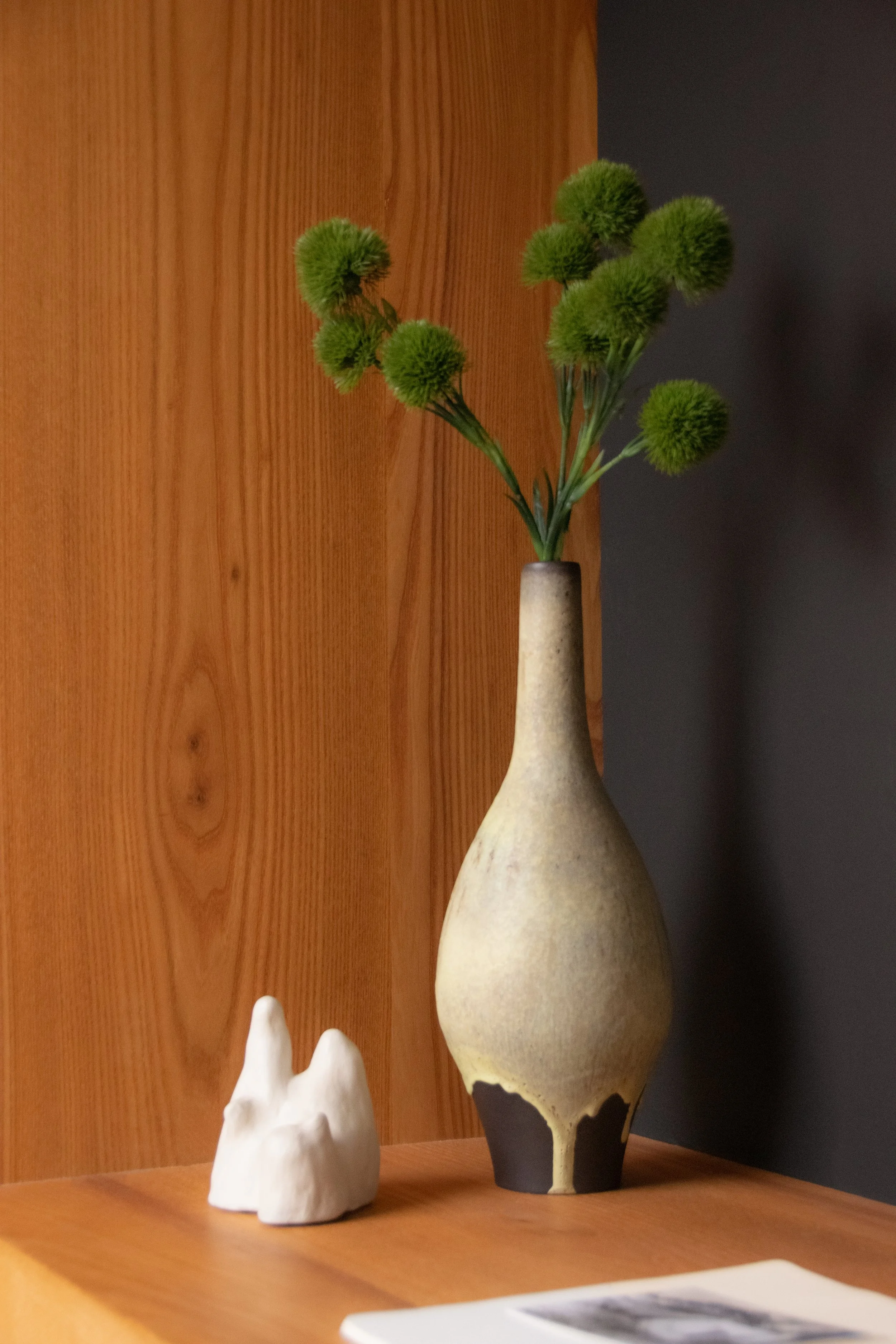 Handmade ceramic objects and natural textures styled within warm oak shelving