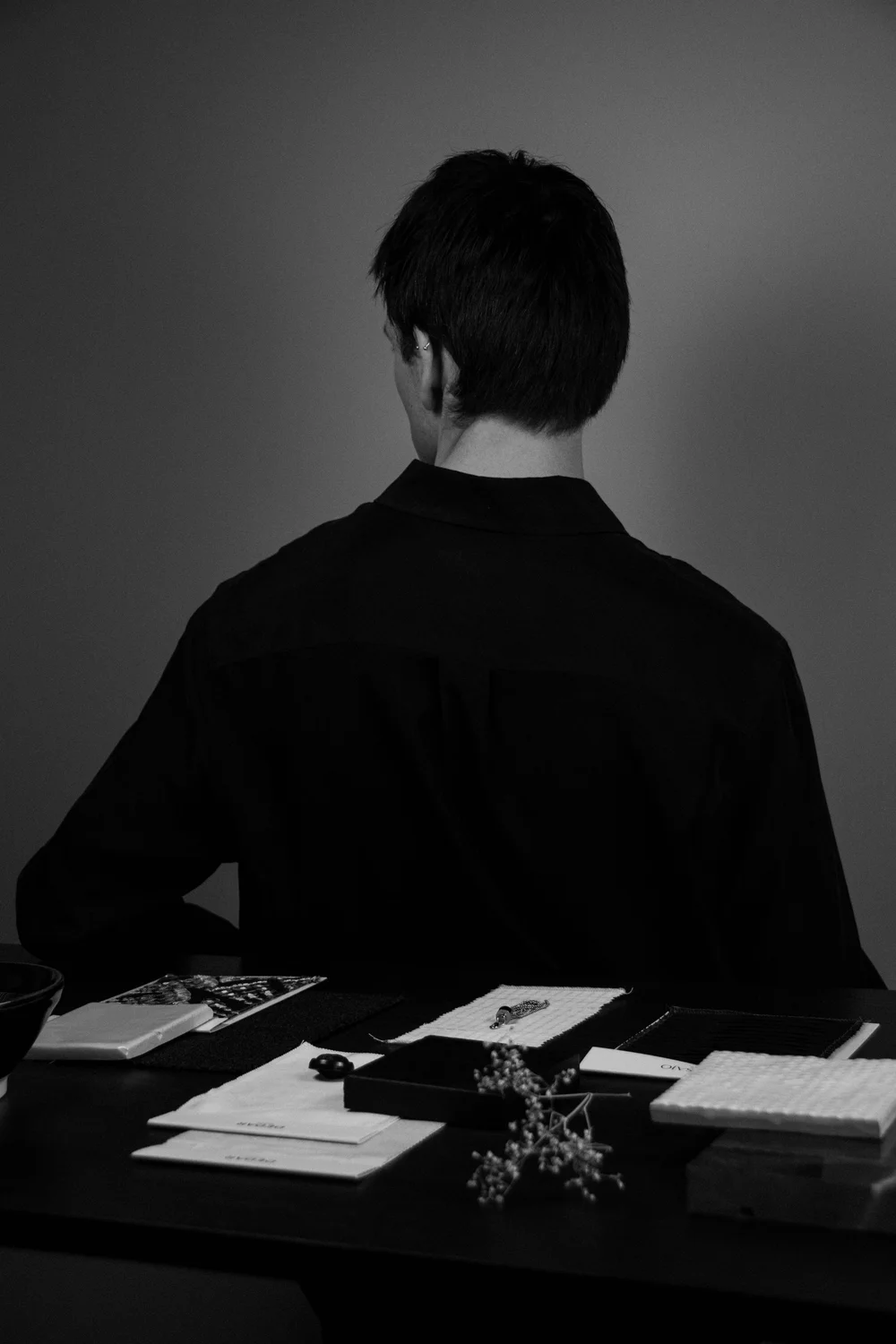 Joost Laméris, founder of Studio Cér, seen from behind at a table of material and textile samples.