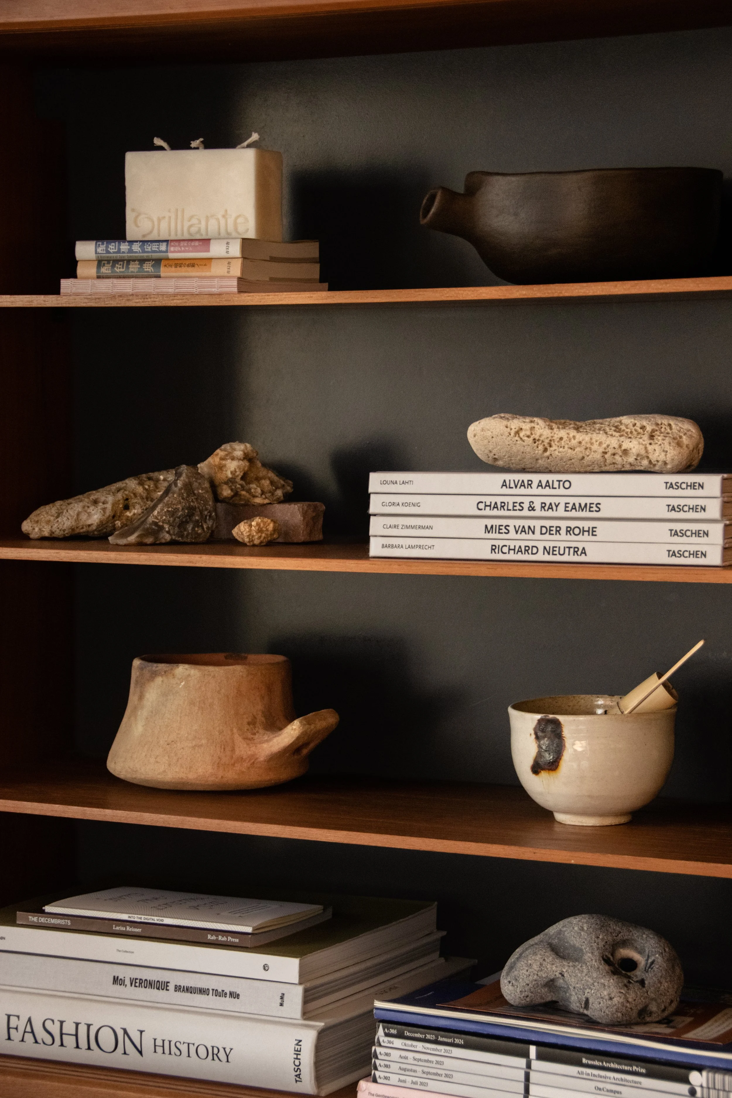 Curated shelving with ceramics, books and natural objects within warm contemporary interior