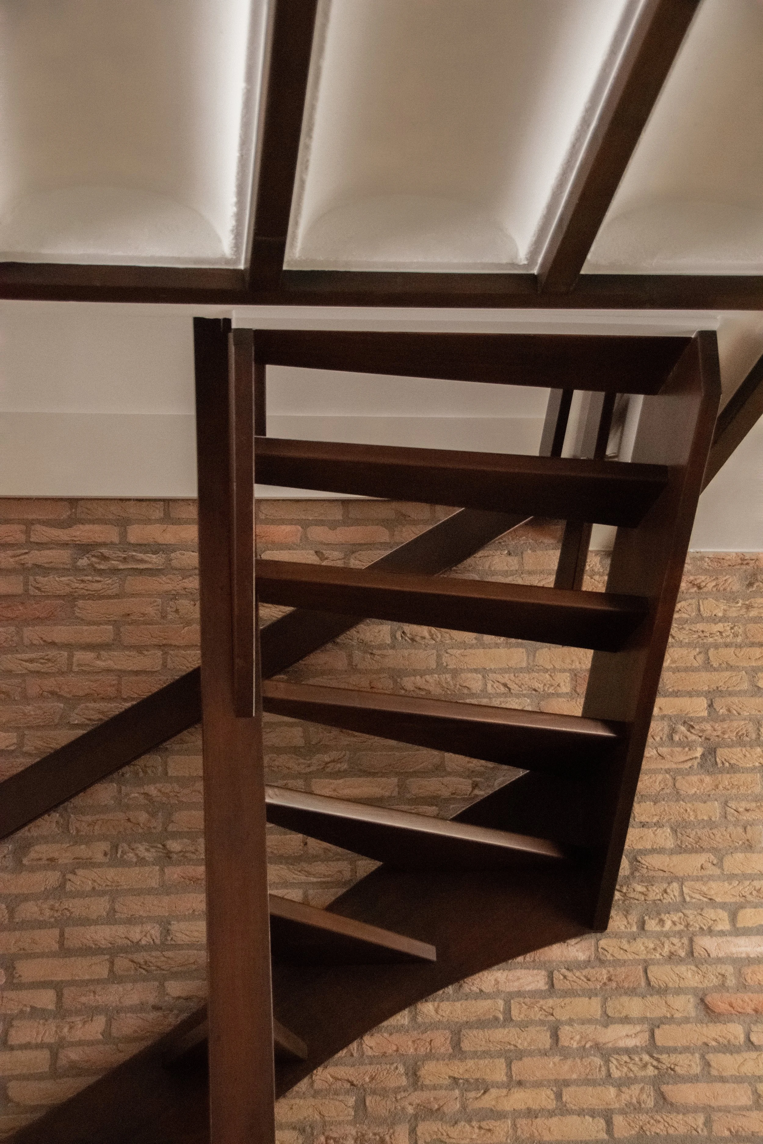 Timber staircase detail against exposed brick wall