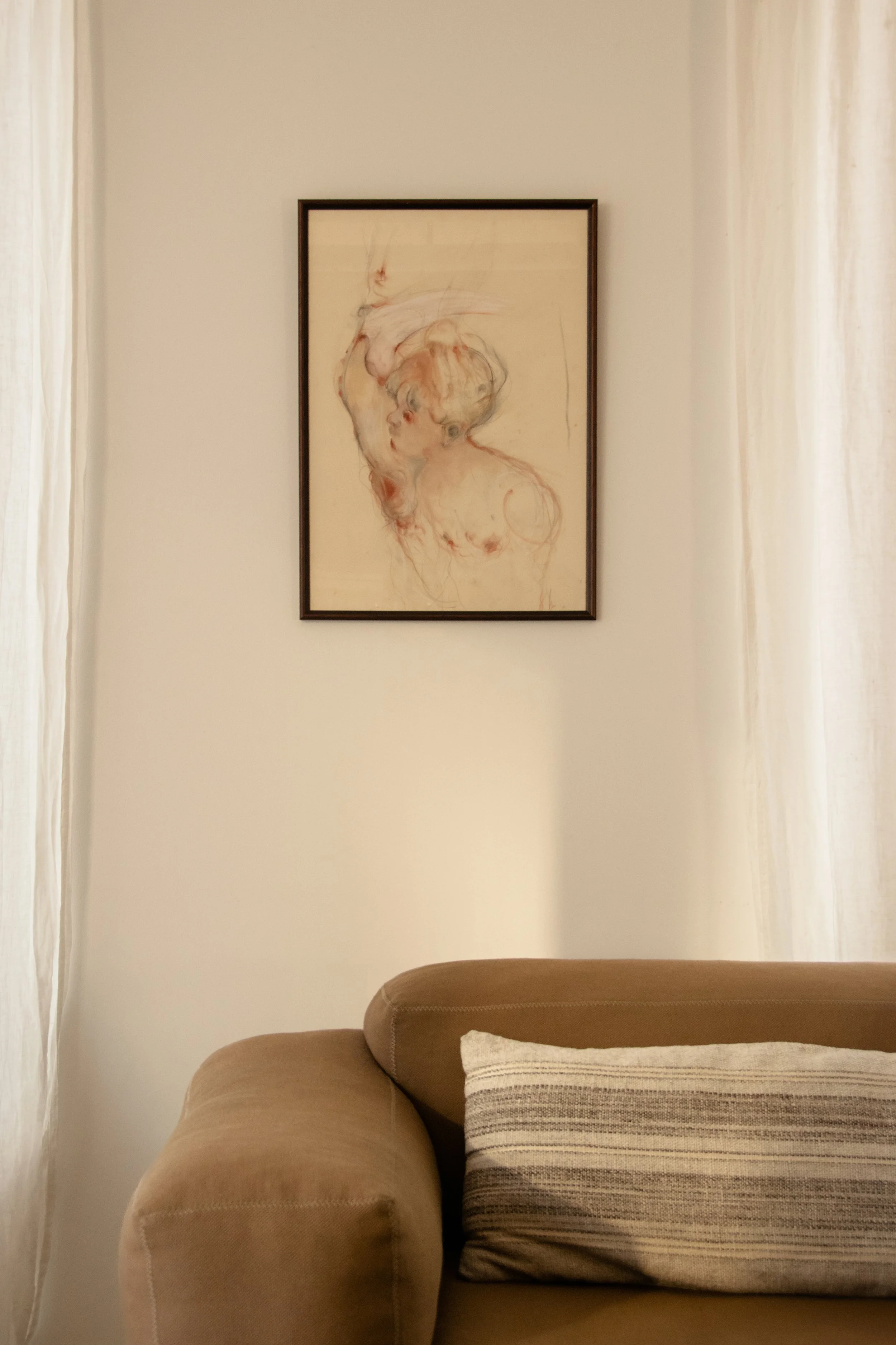 Contemporary artwork and warm brown sofa within a calm and restrained living space
