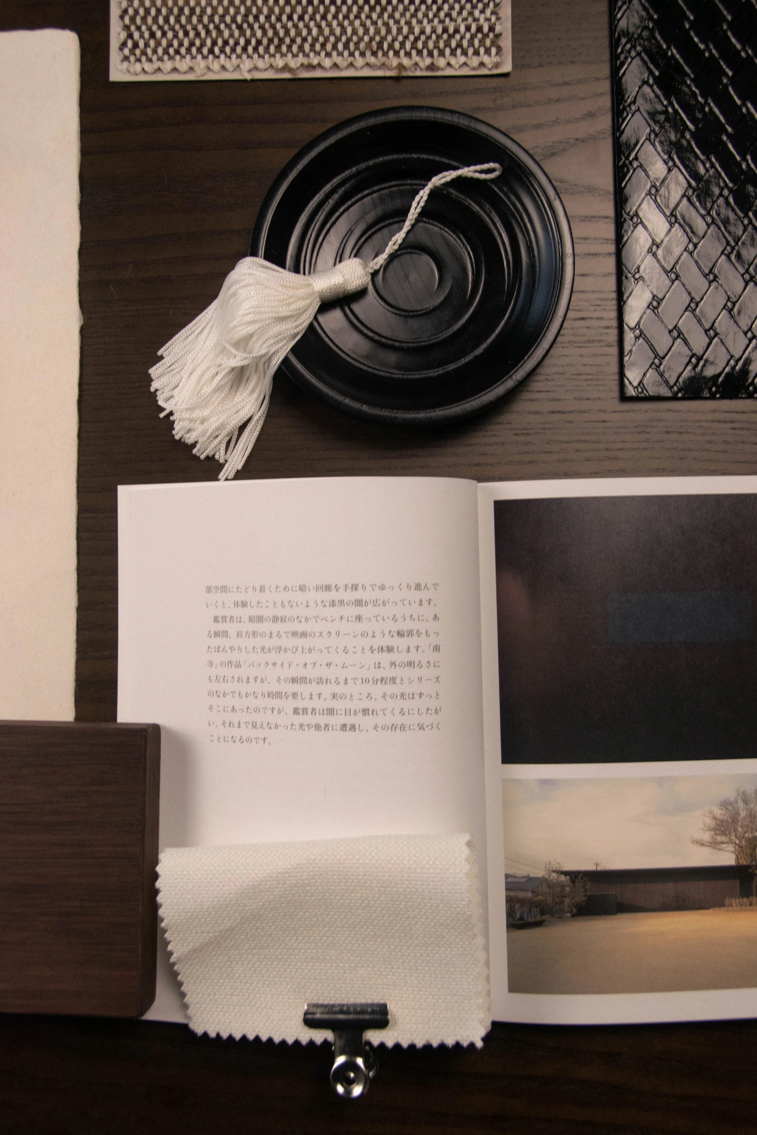 Black lacquered dish with a knotted cream tassel, styled with woven textile samples on a Studio Cér material board.