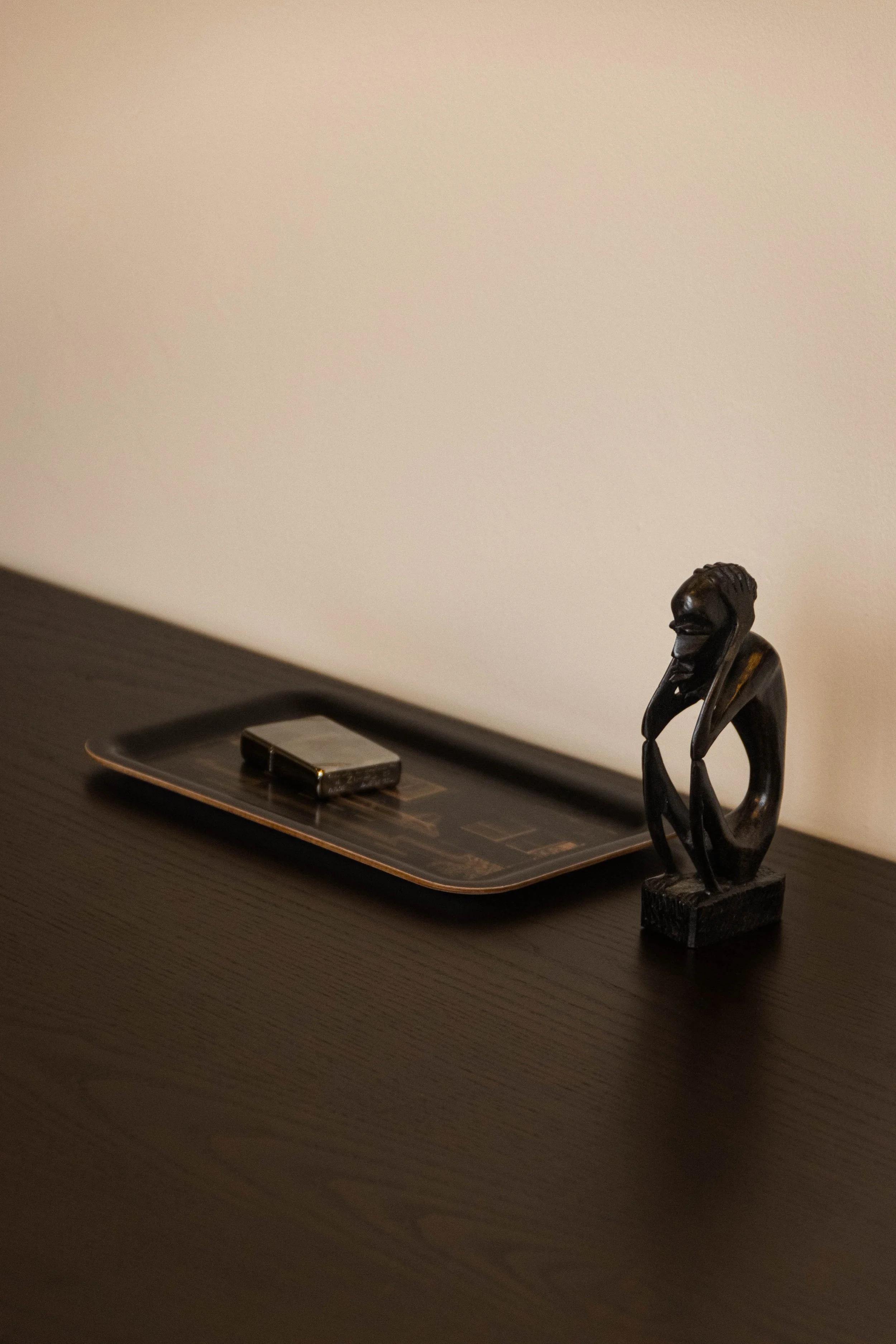 Desk detail with a tray, lighter and small sculptural figurine in the Reflections Office