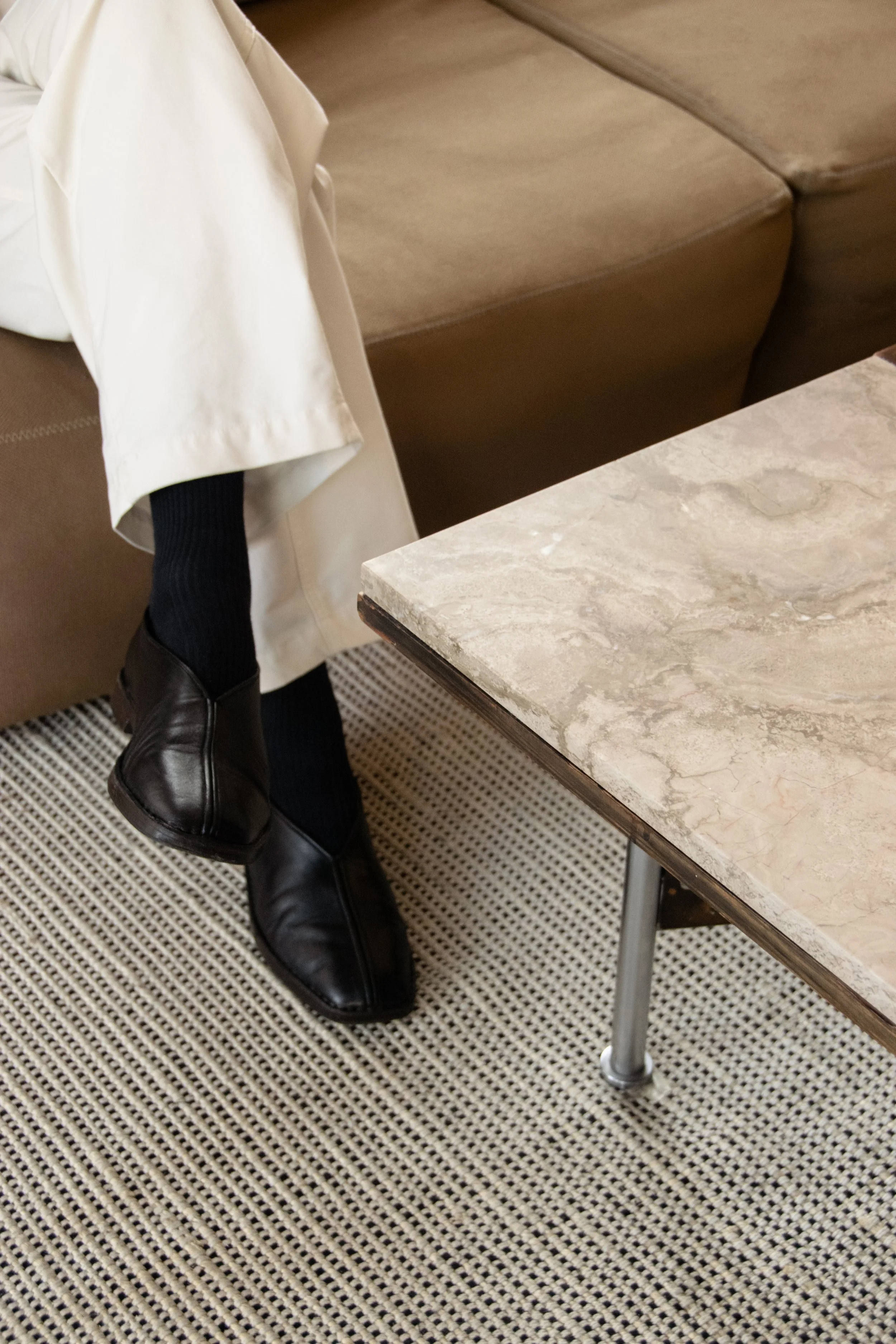 Material detail featuring natural stone, warm brown sofa and textured rug