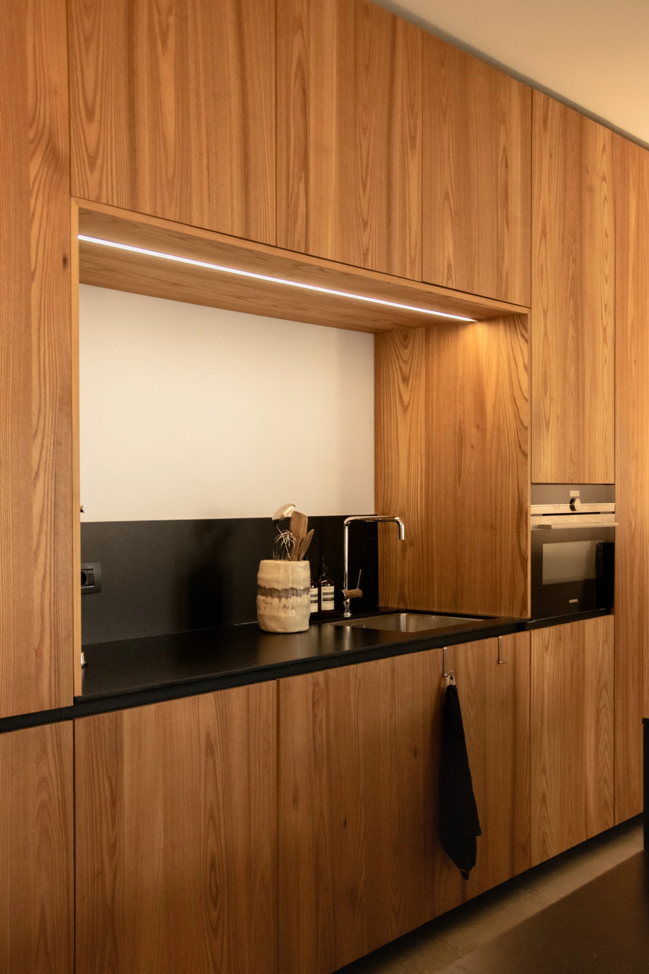 Contemporary oak kitchen with integrated storage and minimal material palette in Antwerp apartment
