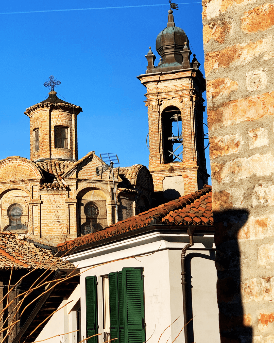 Close-up view of historic church buildings with brick towers and domes, set against a clear blue sky.
