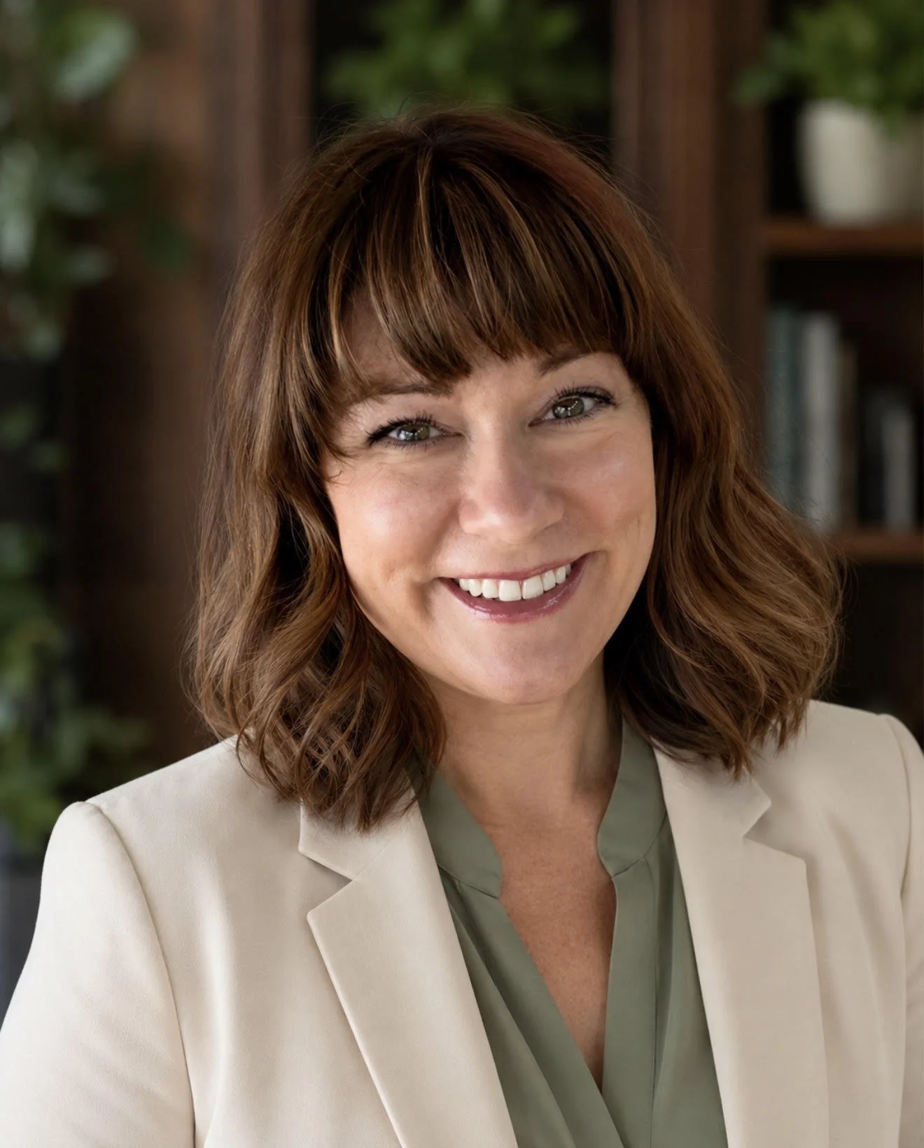 Claire Rivera smiling in a cream blazer, professional portrait for her leadership and writing website.