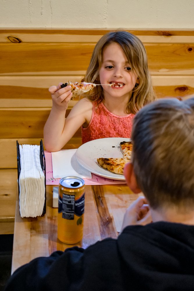 Happy child taking a bite of cheesy pizza
