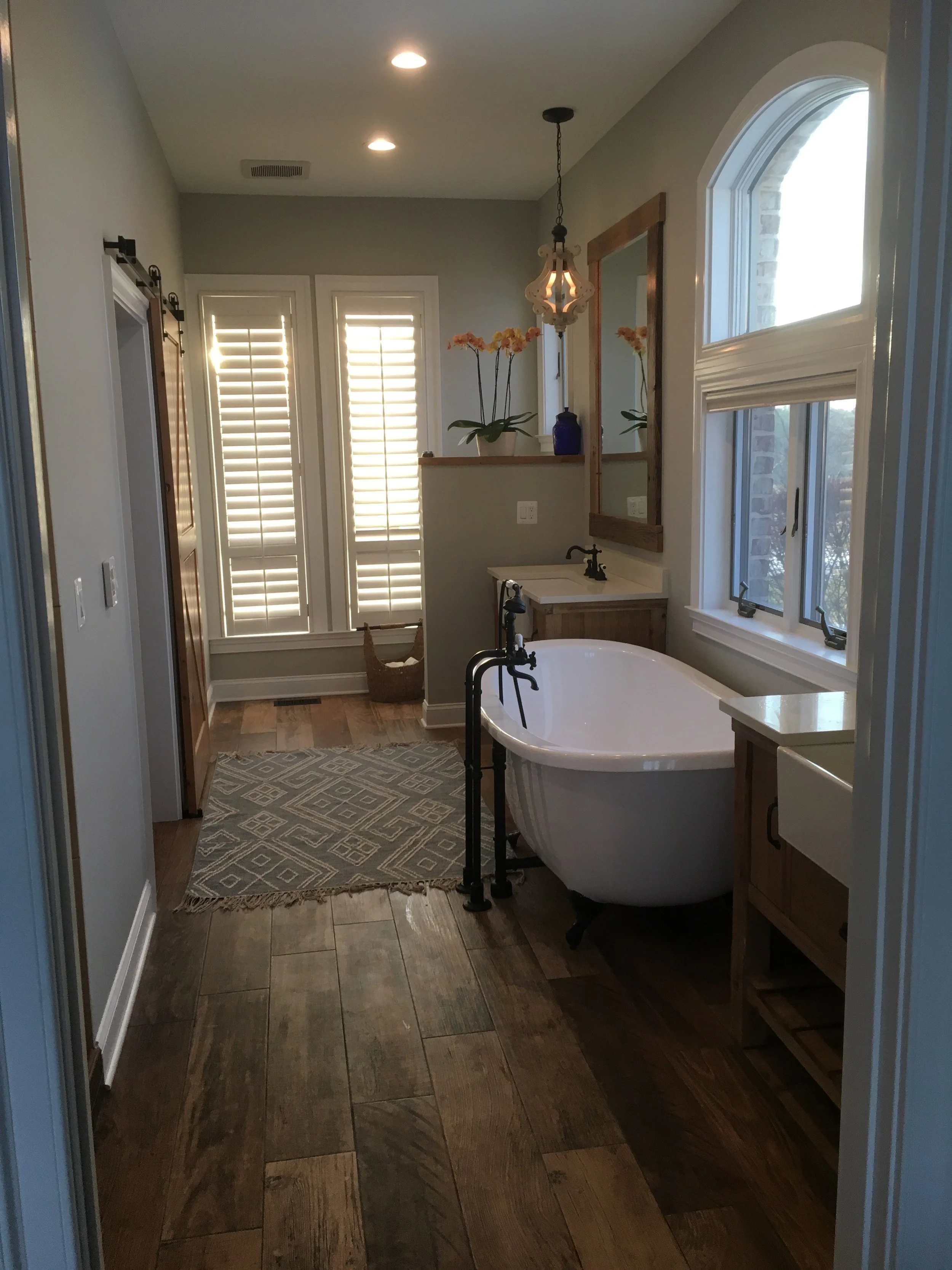 Farmhouse master bathroom with soaking tub, large format plank tiles, barn doors and double vanity