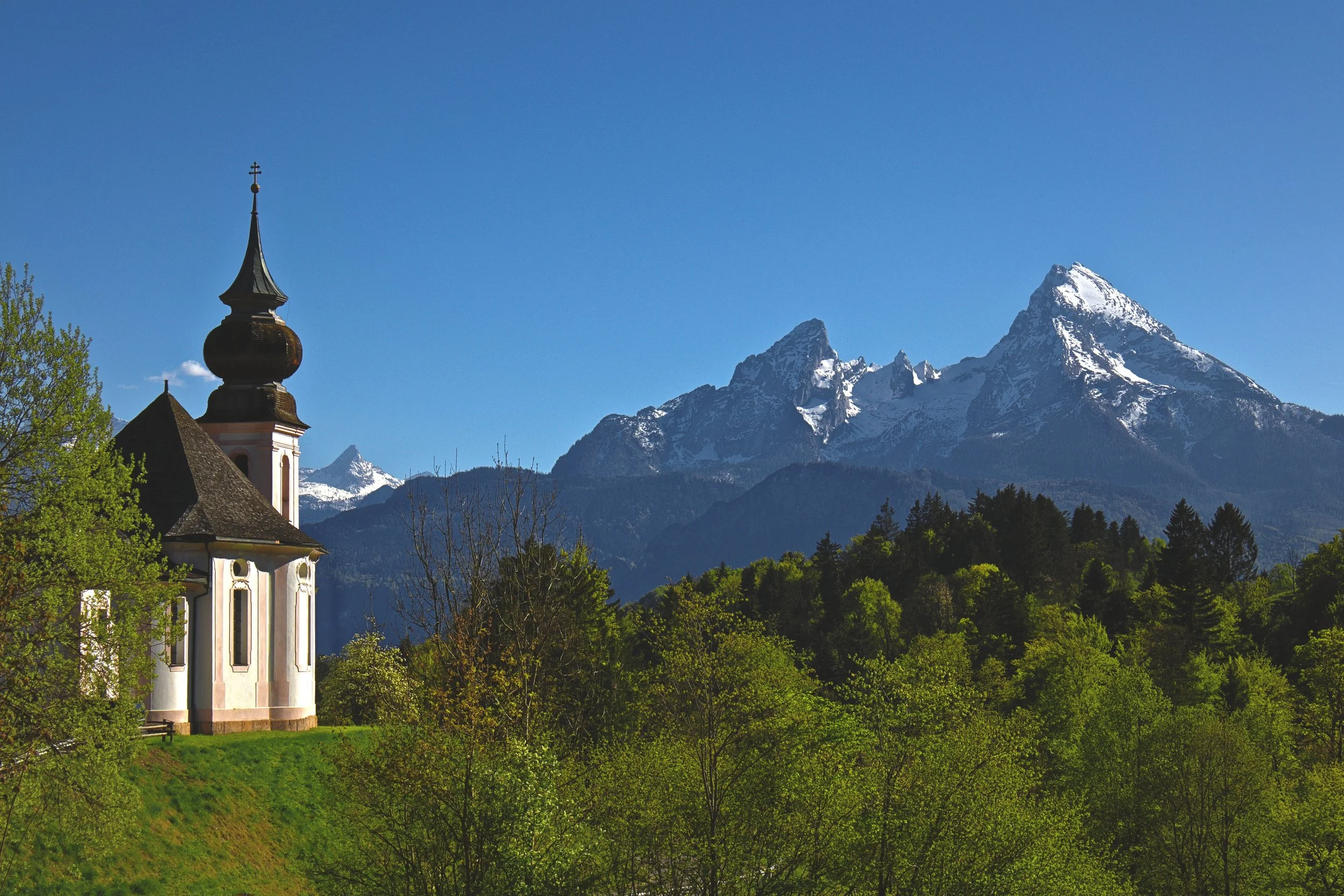 Wallfahrtskirche Maria Gern mit Blick auf den schneebedeckten Watzmann im Frühling.