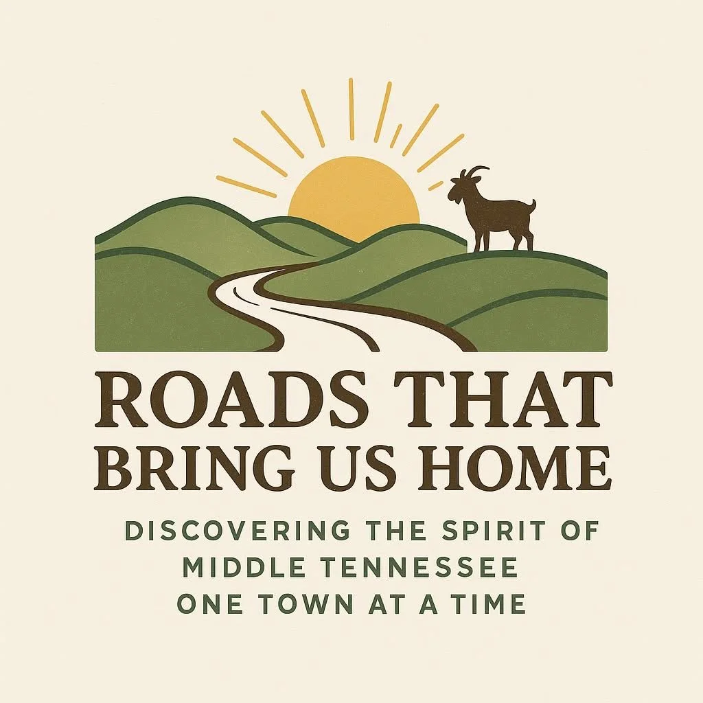 Illustration of a sunrise over green hills with a winding road and a goat standing on the hilltop. The text reads 'Roads That Bring Us Home' and 'Discovering the Spirit of Middle Tennessee One Town at a Time.'