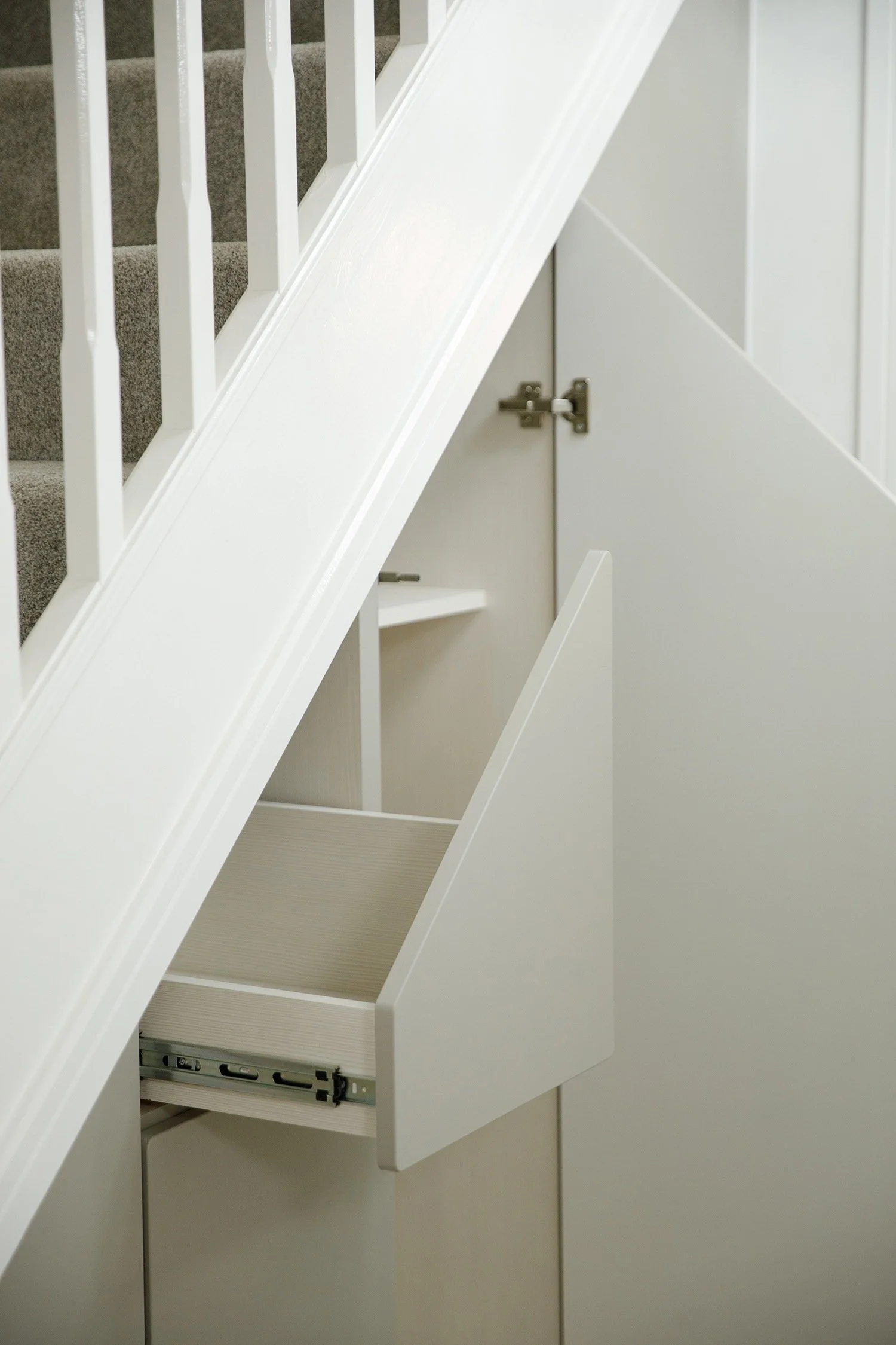 Inner side of a white kitchen cabinet with the door open, revealing drawer slides inside.