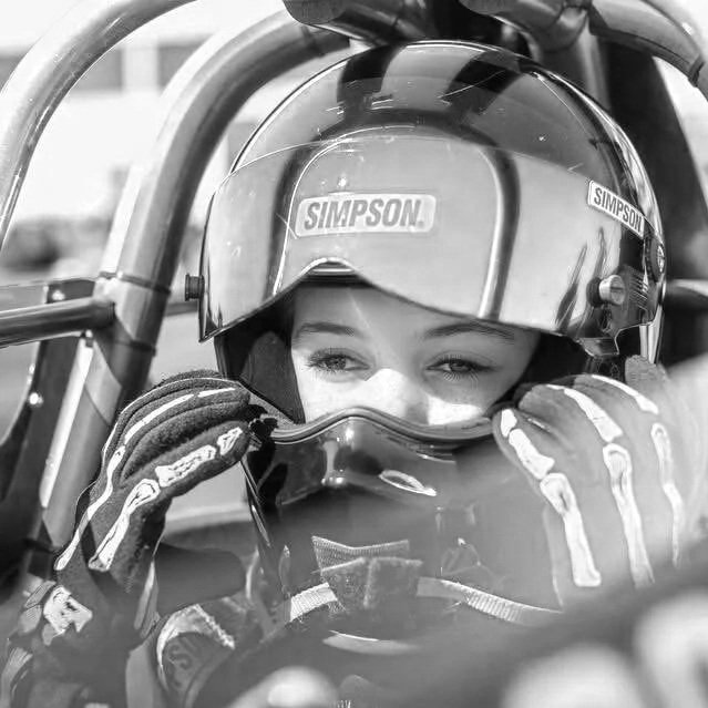 Young woman in racing helmet and gloves sitting in a race car