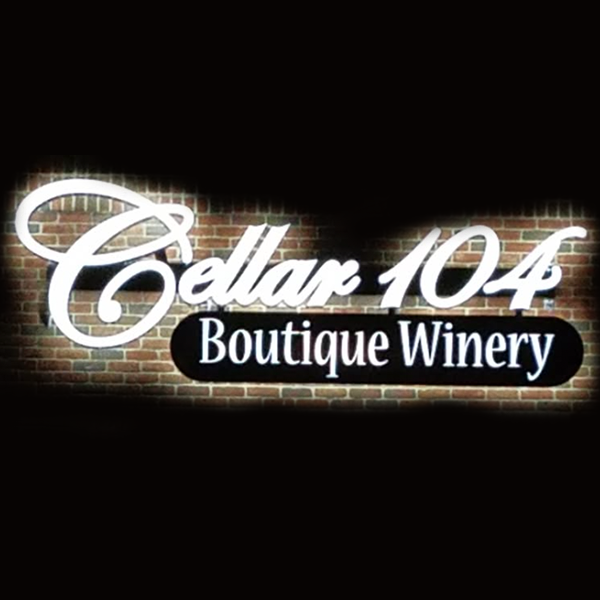 illuminated sign for Cellar 104 Boutique Winery against a brick wall.