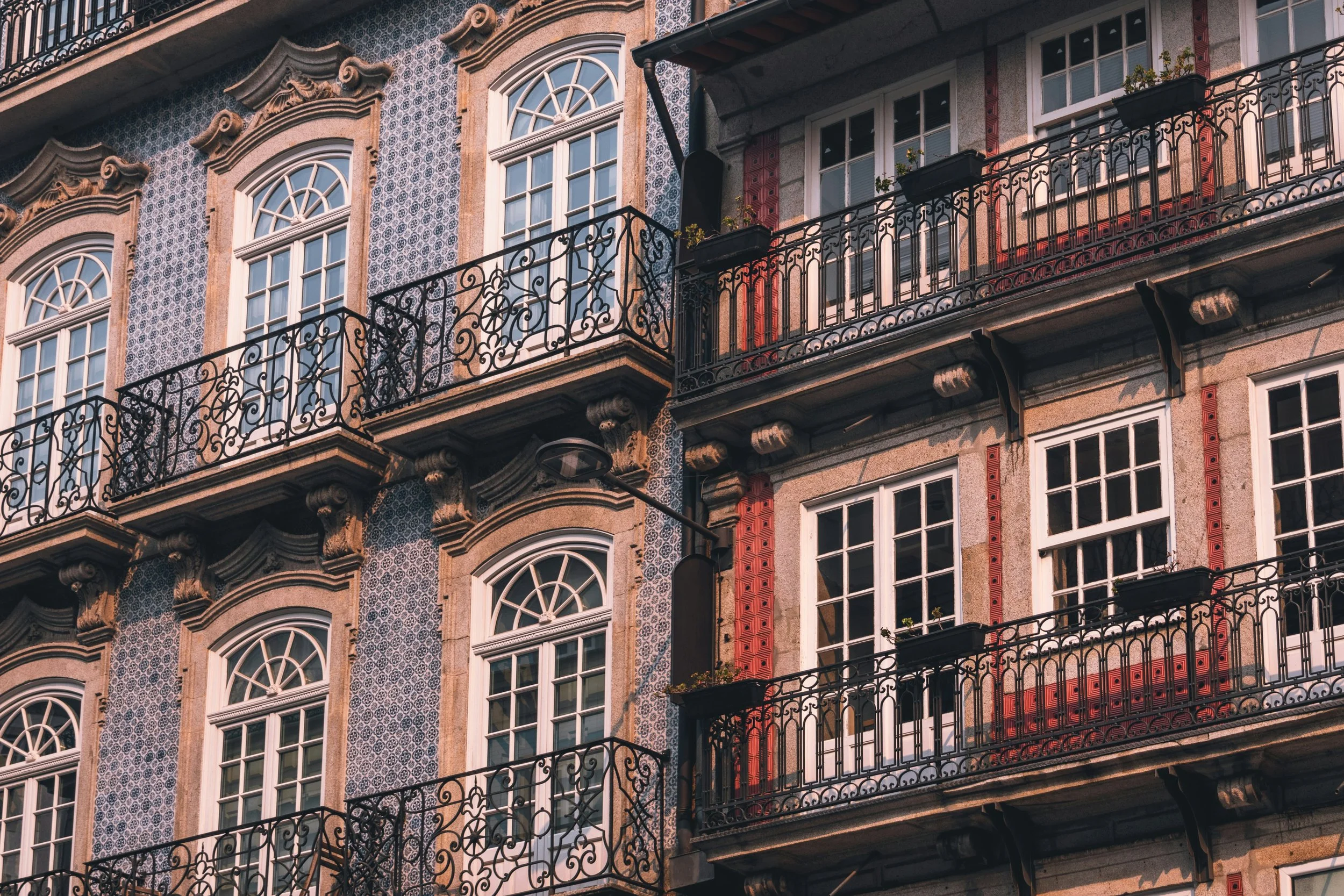 Facade of a historic building with ornate balconies, large arched windows, and decorative tilework.