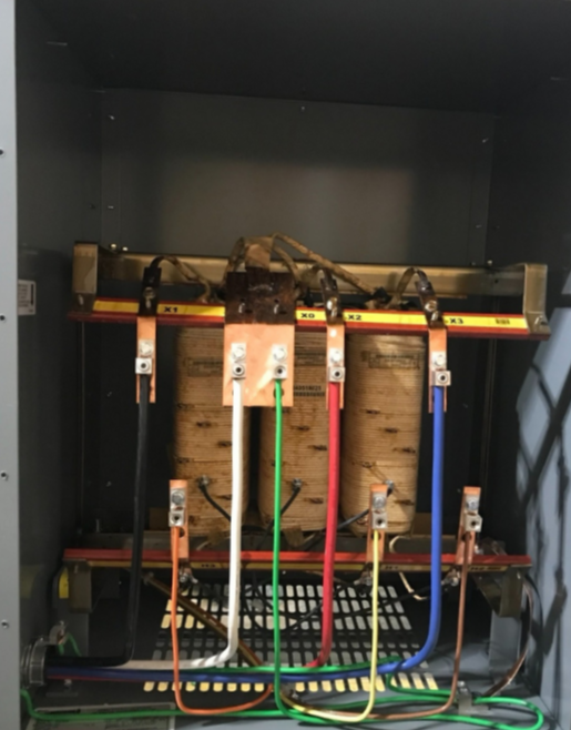 Inside of an electrical panel with multiple colored wires connected to a transformer or switchgear.