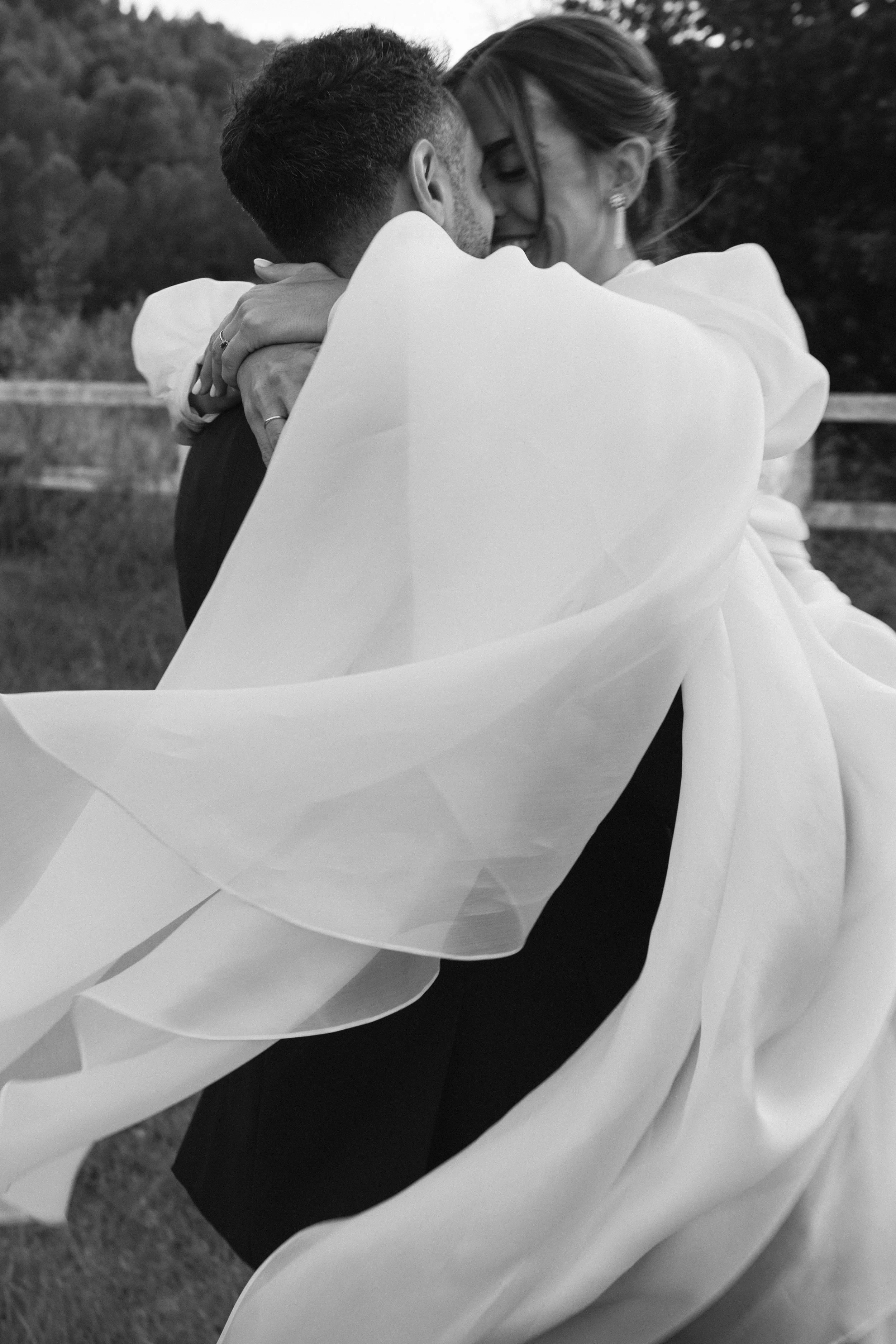 Pareja bailando y abrazados en un ambiente al aire libre, vestido elegante, con un fondo de naturaleza.