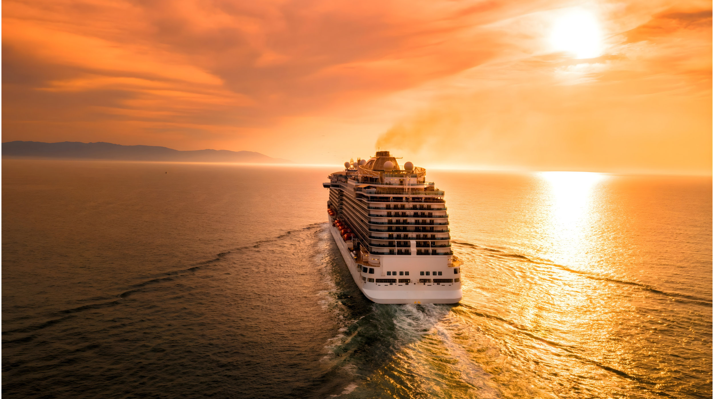 Cruise ship sailing in the open ocean under a golden sunset