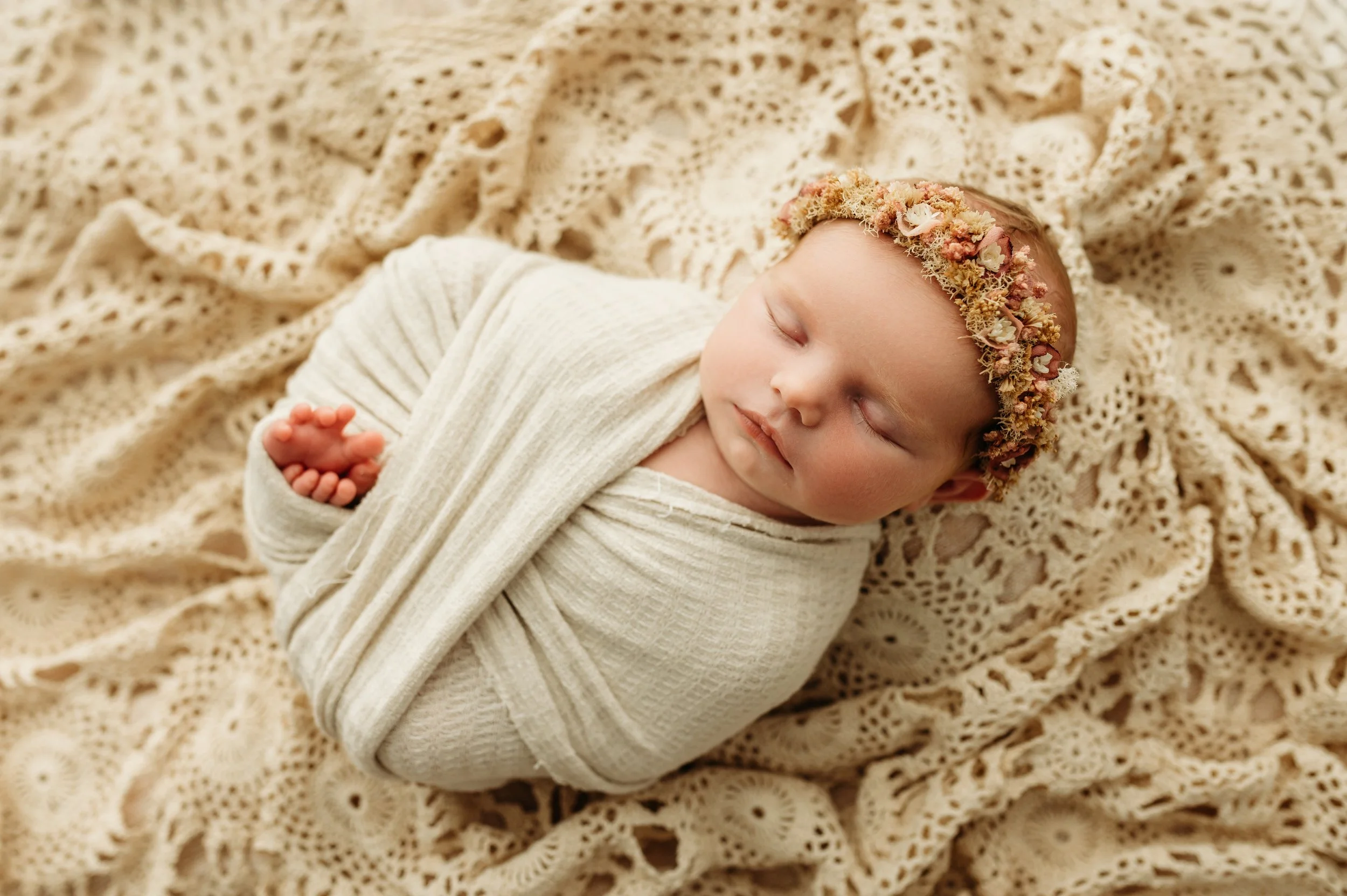 swaddled baby girl with floral headband in nashville, tn studio that is simple and timeless