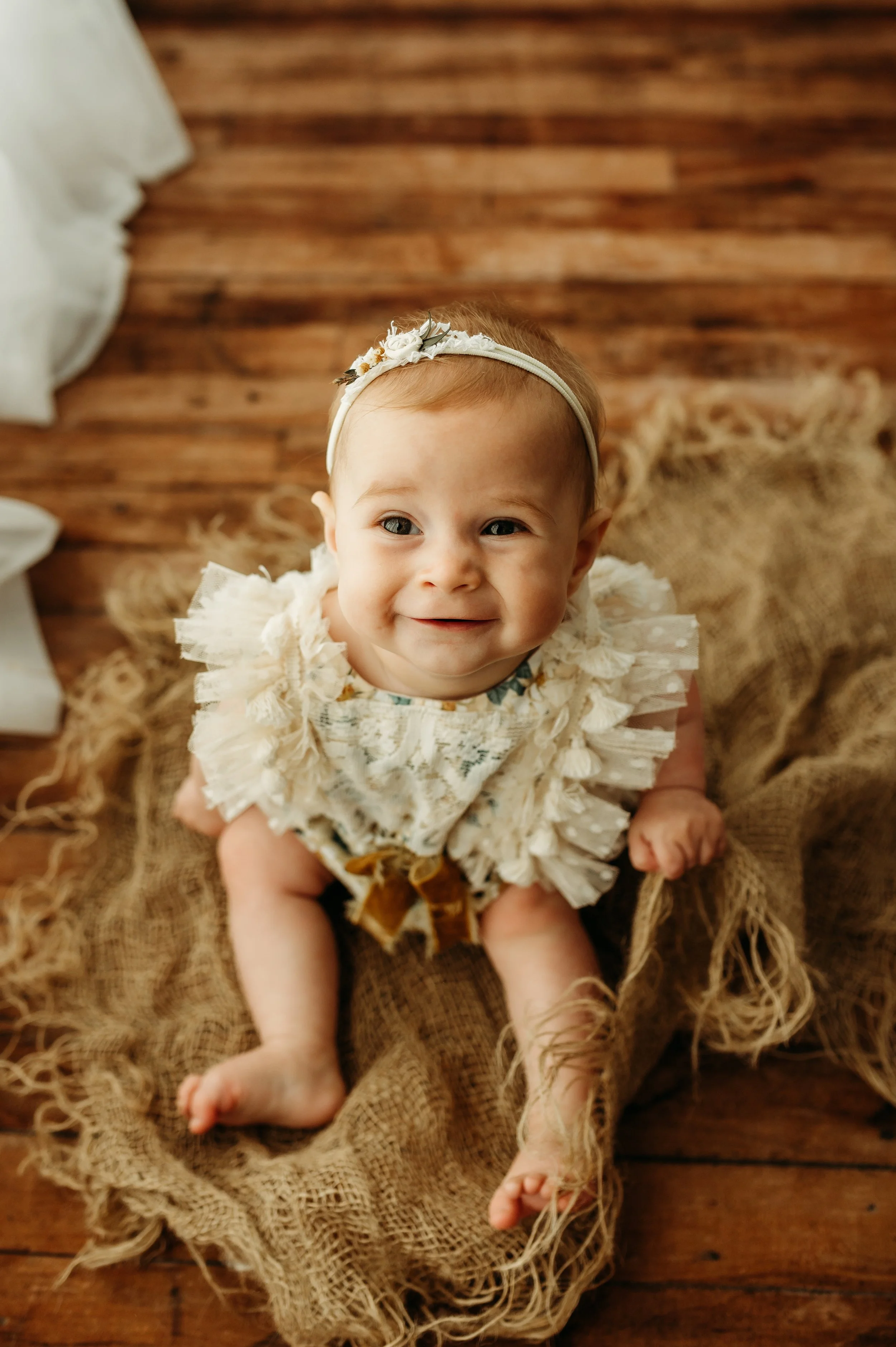 baby girl smiling for her six month milestone session in a clarksville tennessee studio using natural light and providing a client closet
