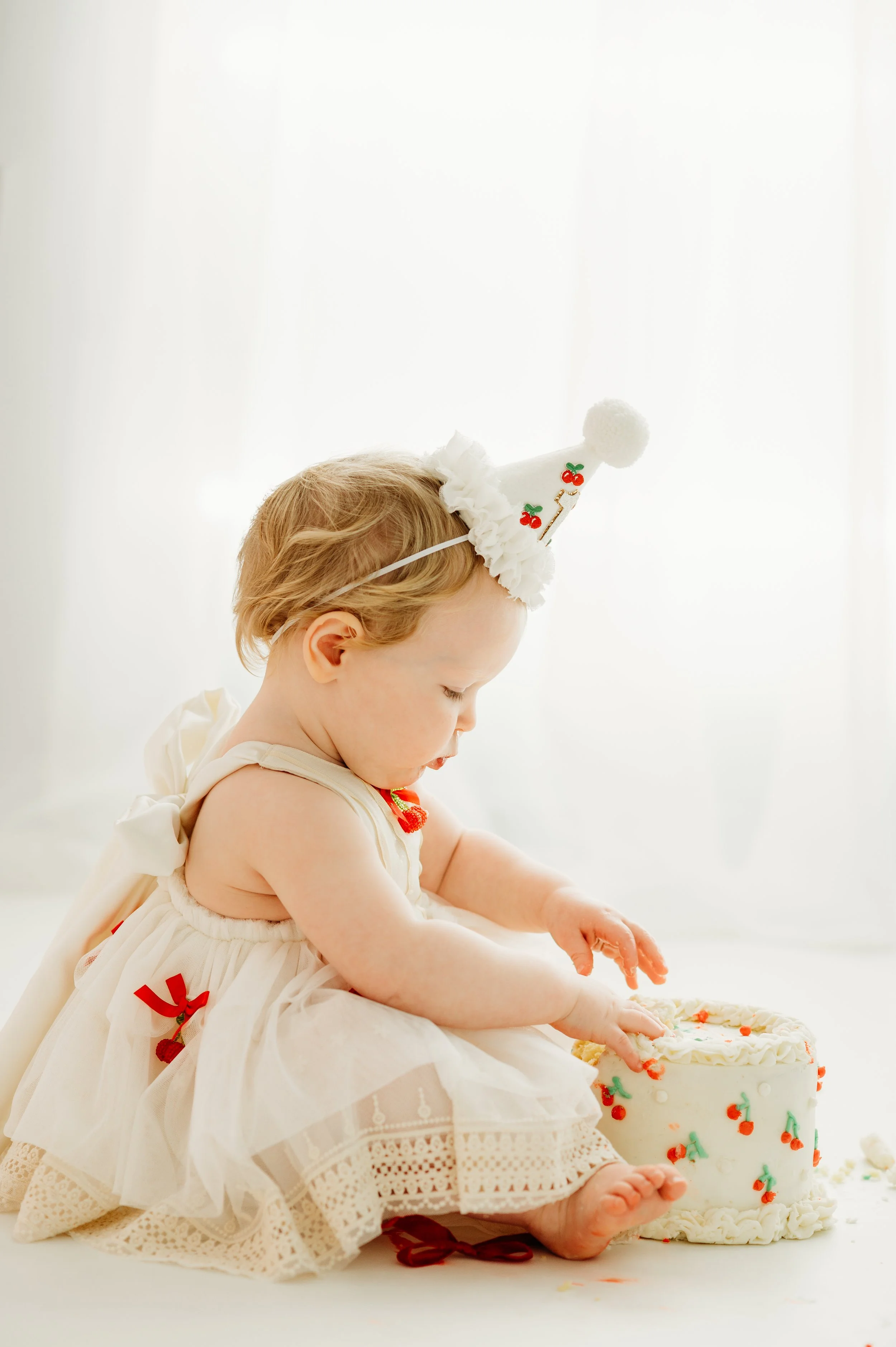 Nashville, Tennessee baby girl cake smash session to celebrate her first birthday with a cherry theme in a white studio