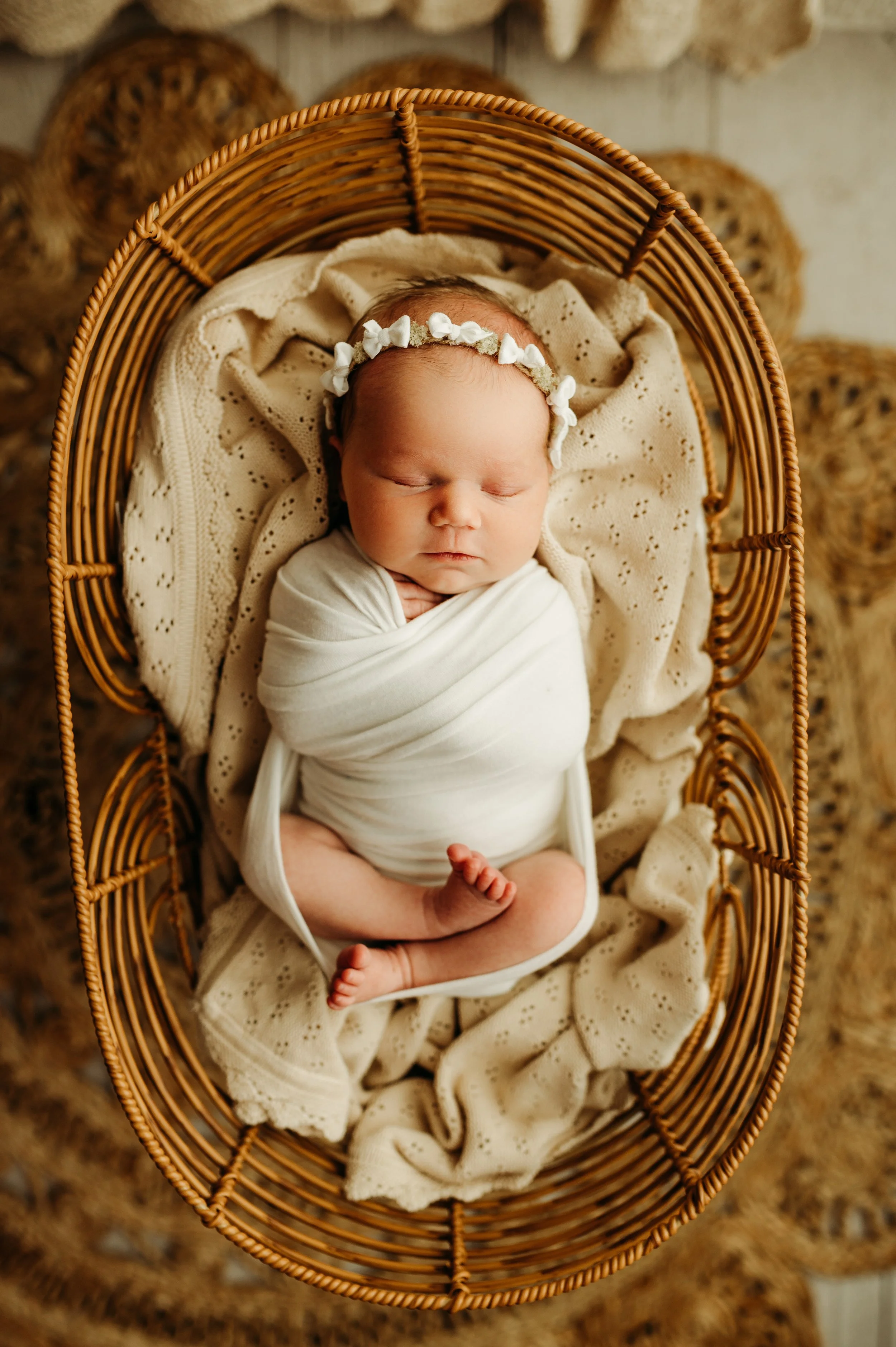 nashville, TN newborn baby girl swaddled in a beautiful crib with an adorable headband for her newborn photography session