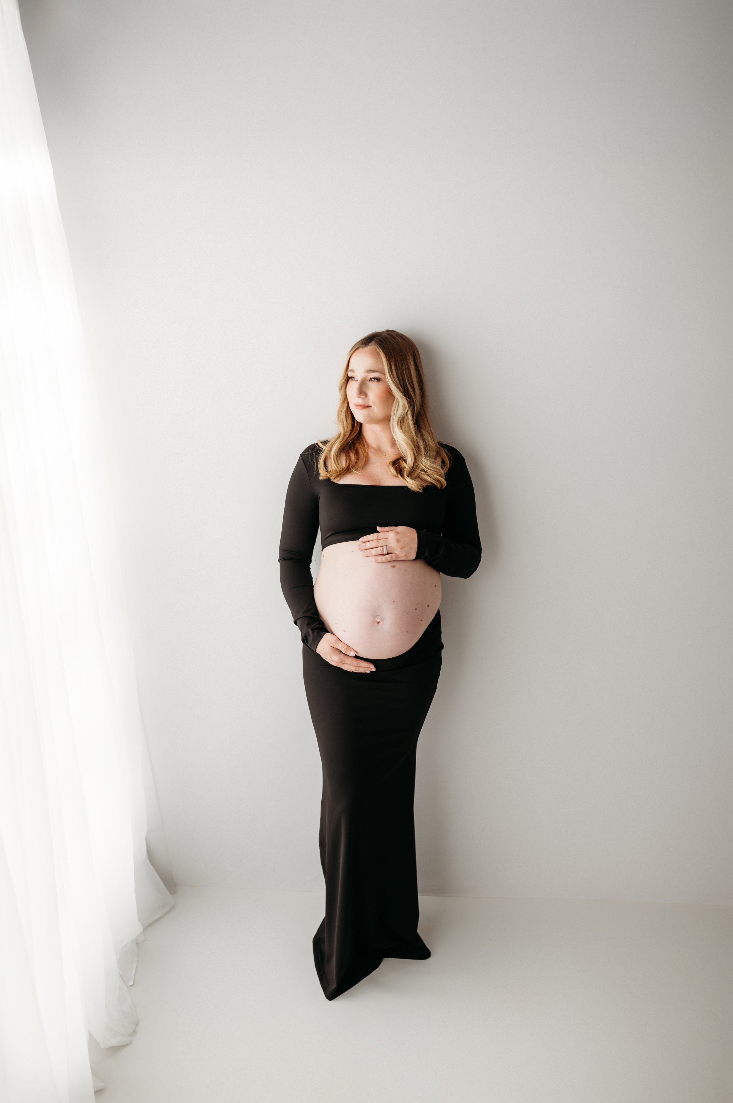 clarksville, tn mom in a white studio for her maternity session using natural light