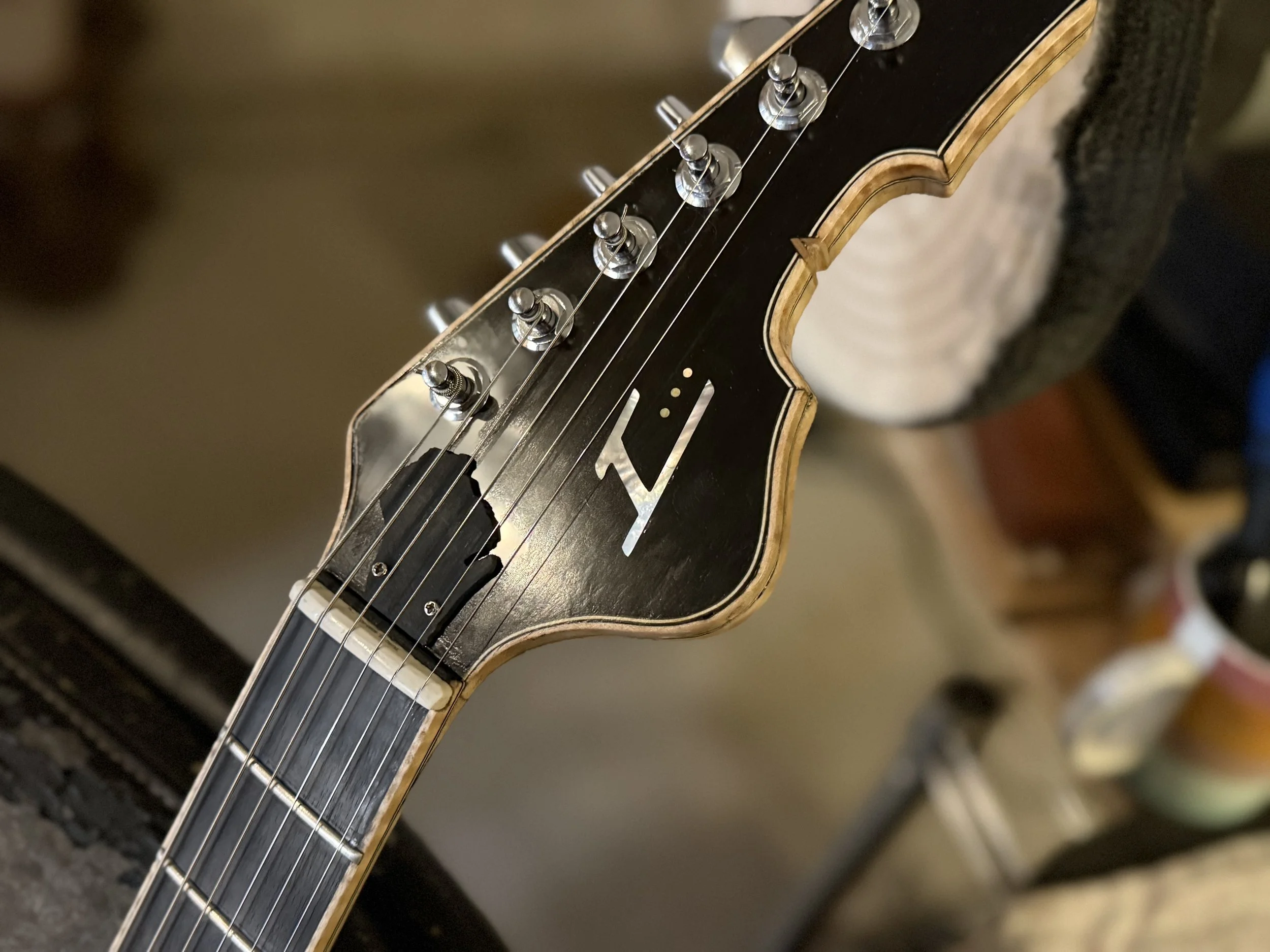 Close-up of a guitar headstock with tuning pegs, strings, and part of the fretboard visible.