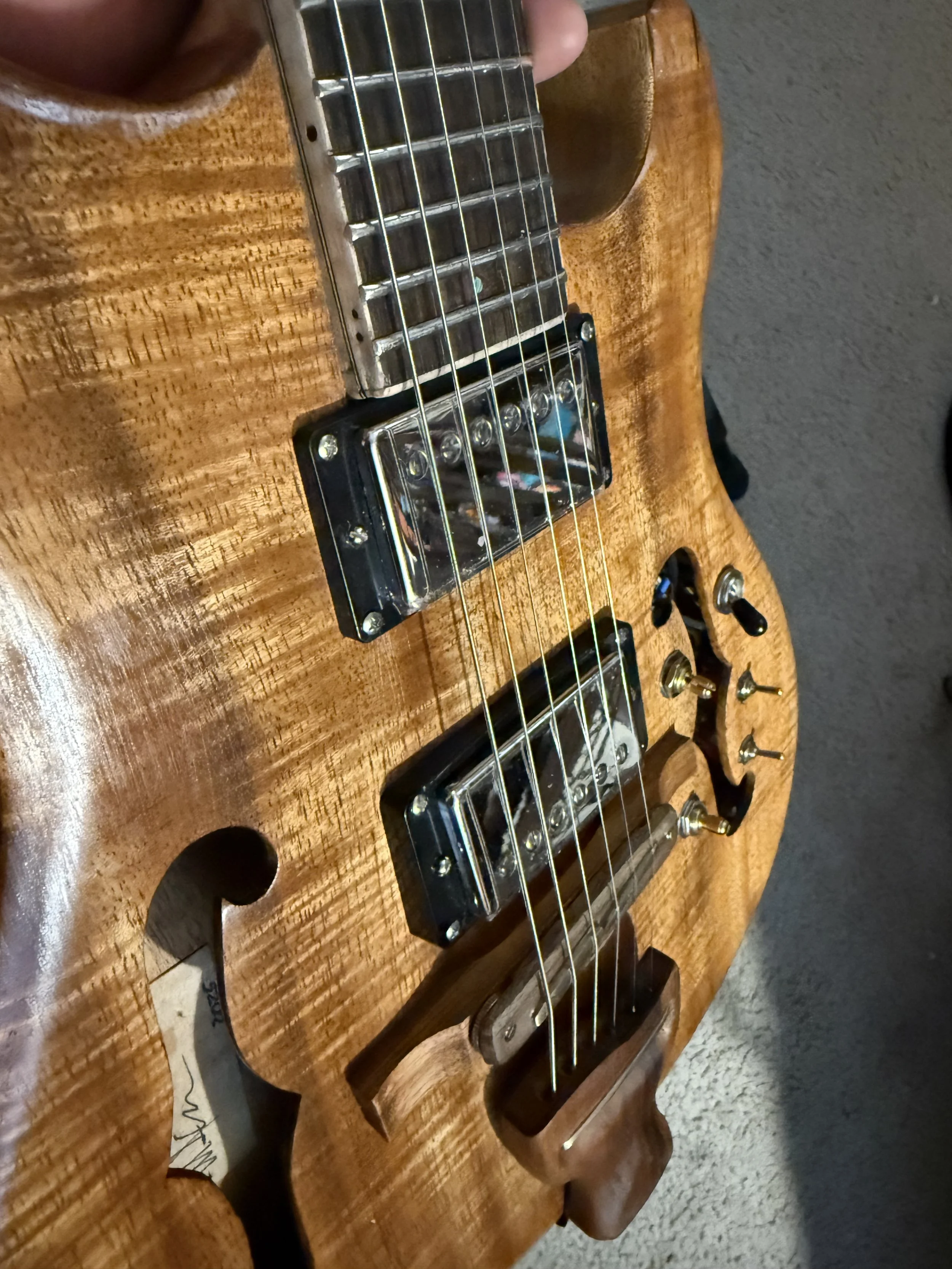 Close-up of a wooden electric guitar, showing strings, pickups, and knobs.