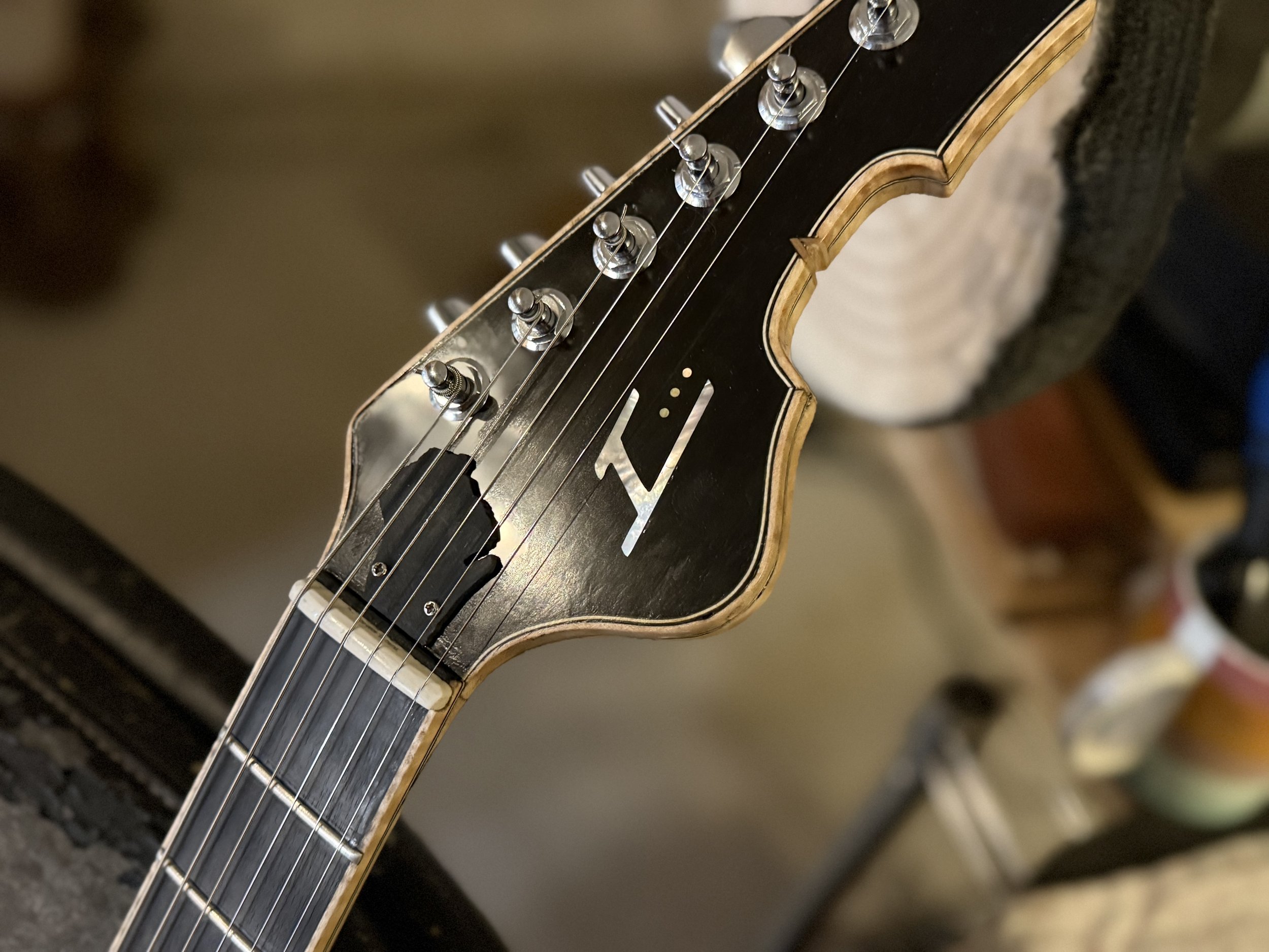 Close-up of an electric guitar neck, focusing on the tuning pegs, headstock, and strings.