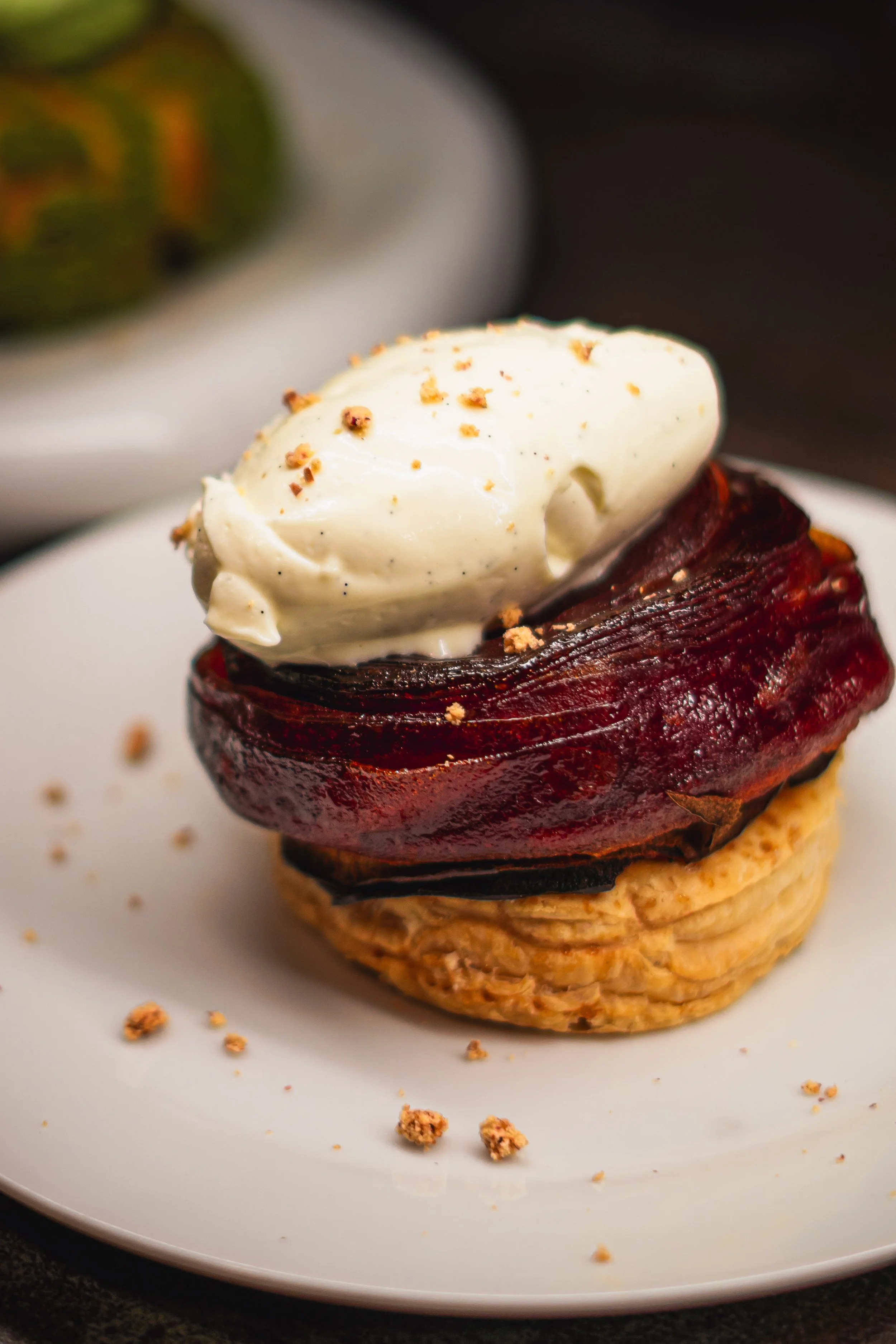 Tartelette aux fruits avec une perle de crème, garnie de noisettes grillées.