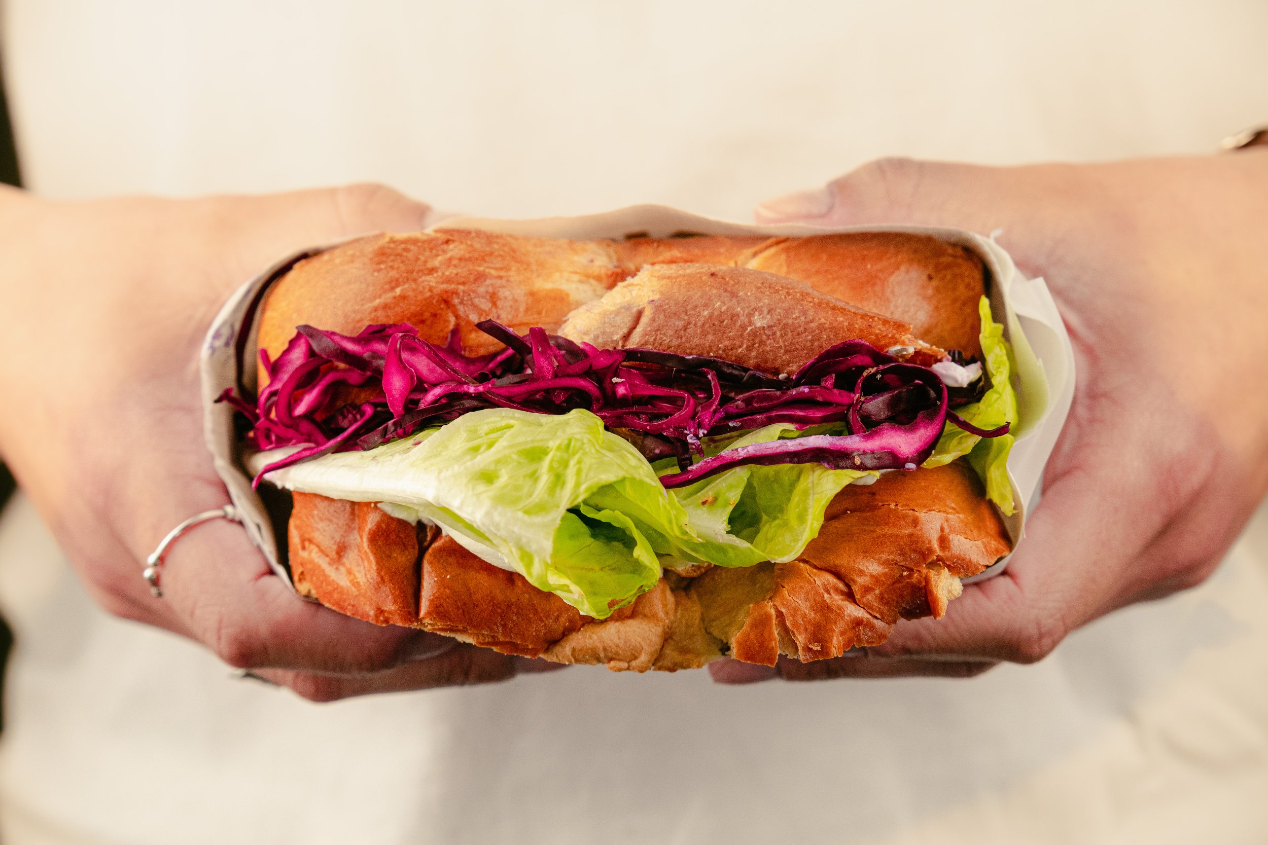 Sandwich avec du pain, de la laitue, du chou rouge et de la viande.