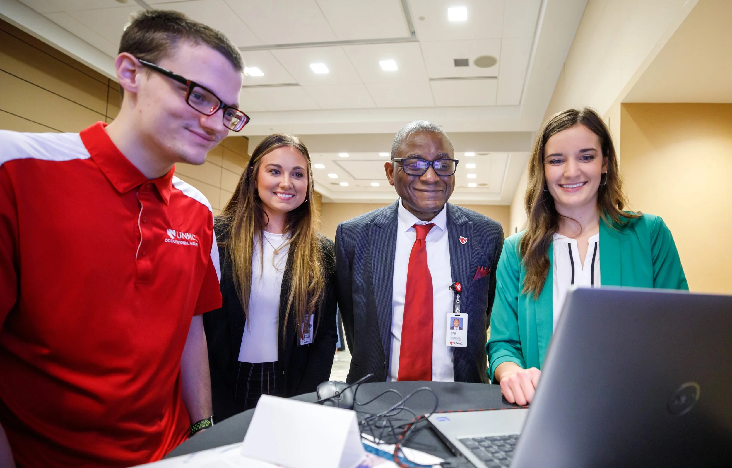 Dr. Dele Davies and students look at e-learning module on laptop screen