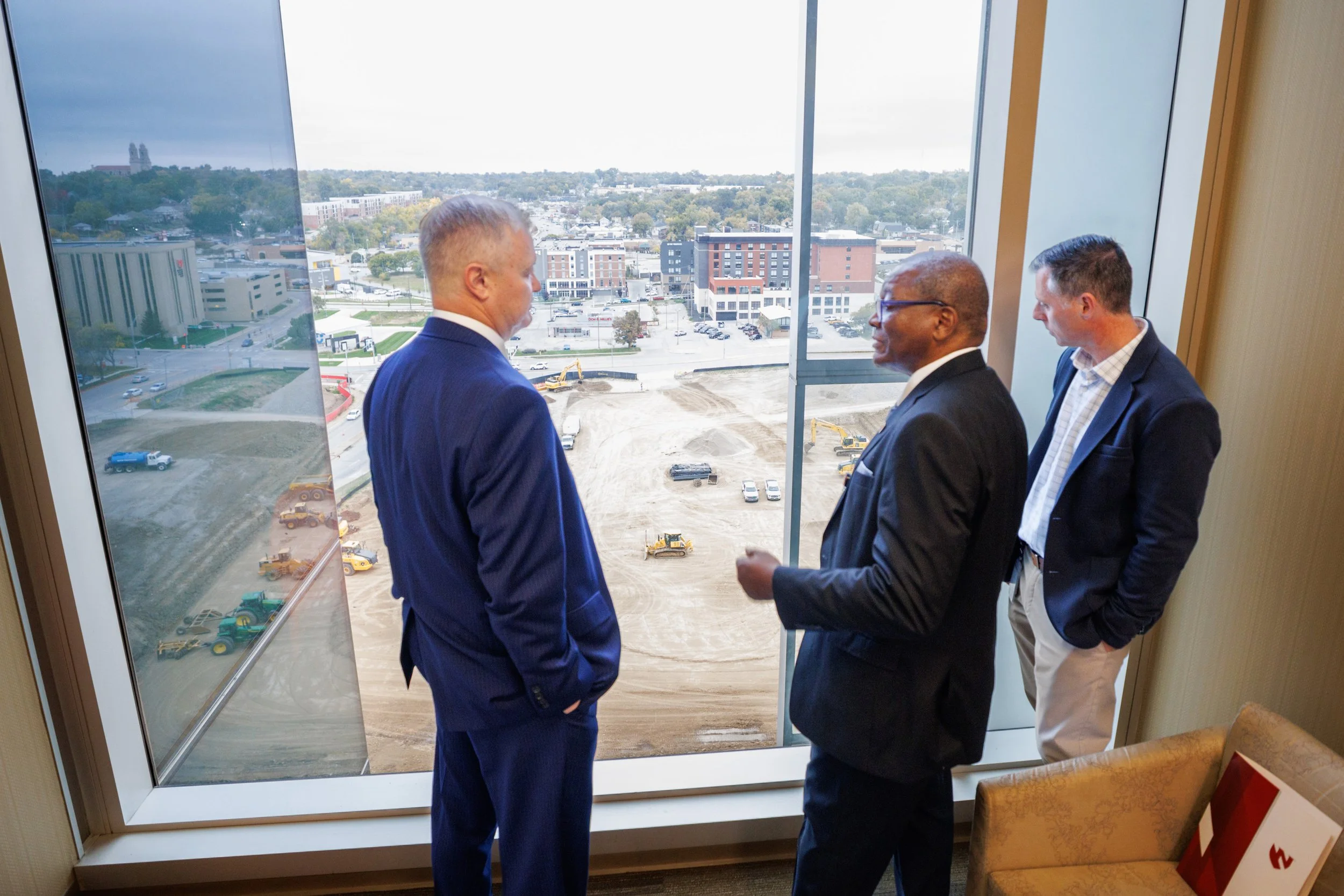 Dr. Dele Davies and NU Board of Regent look out window overlooking Project Health building construction
