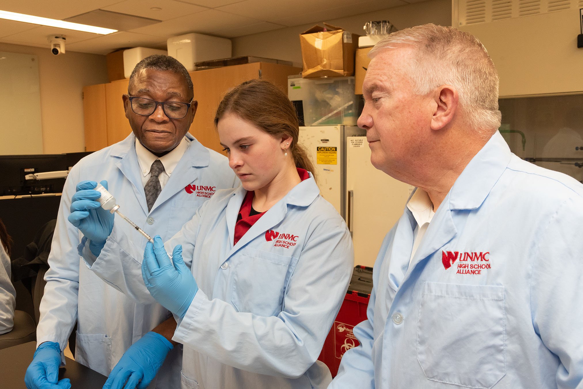 Dr. Dele Davies, NU Regent watch student measure vial in lab