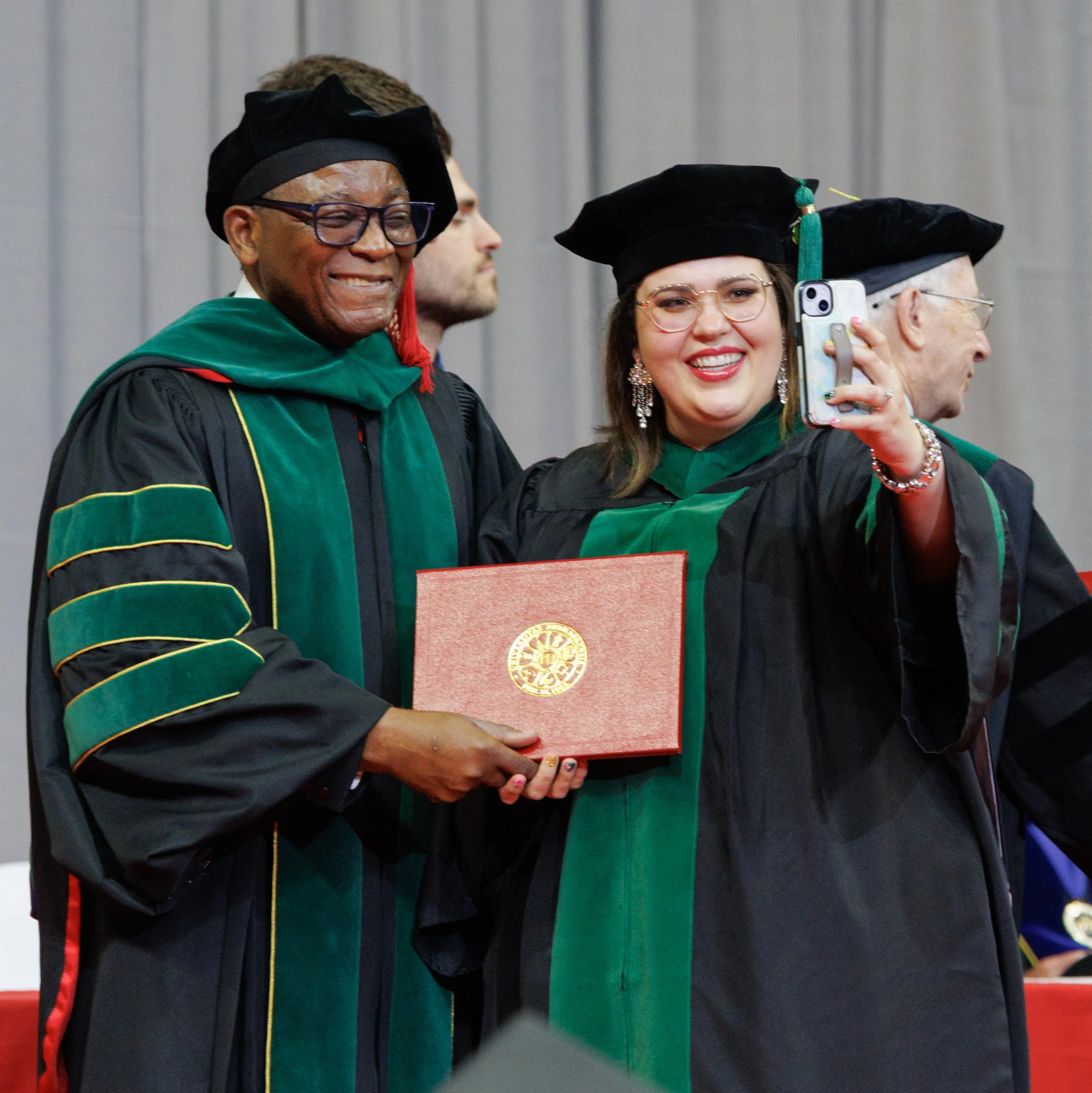 Dr. Dele Davies poses with student at graduation to take selfie