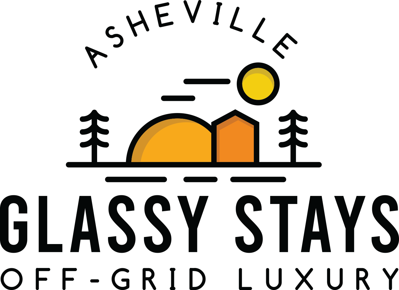 Logo of Glassy Stays featuring a sunset or sunrise with trees and a small house, and the text 'Ashleyville Off-Grid Luxury'