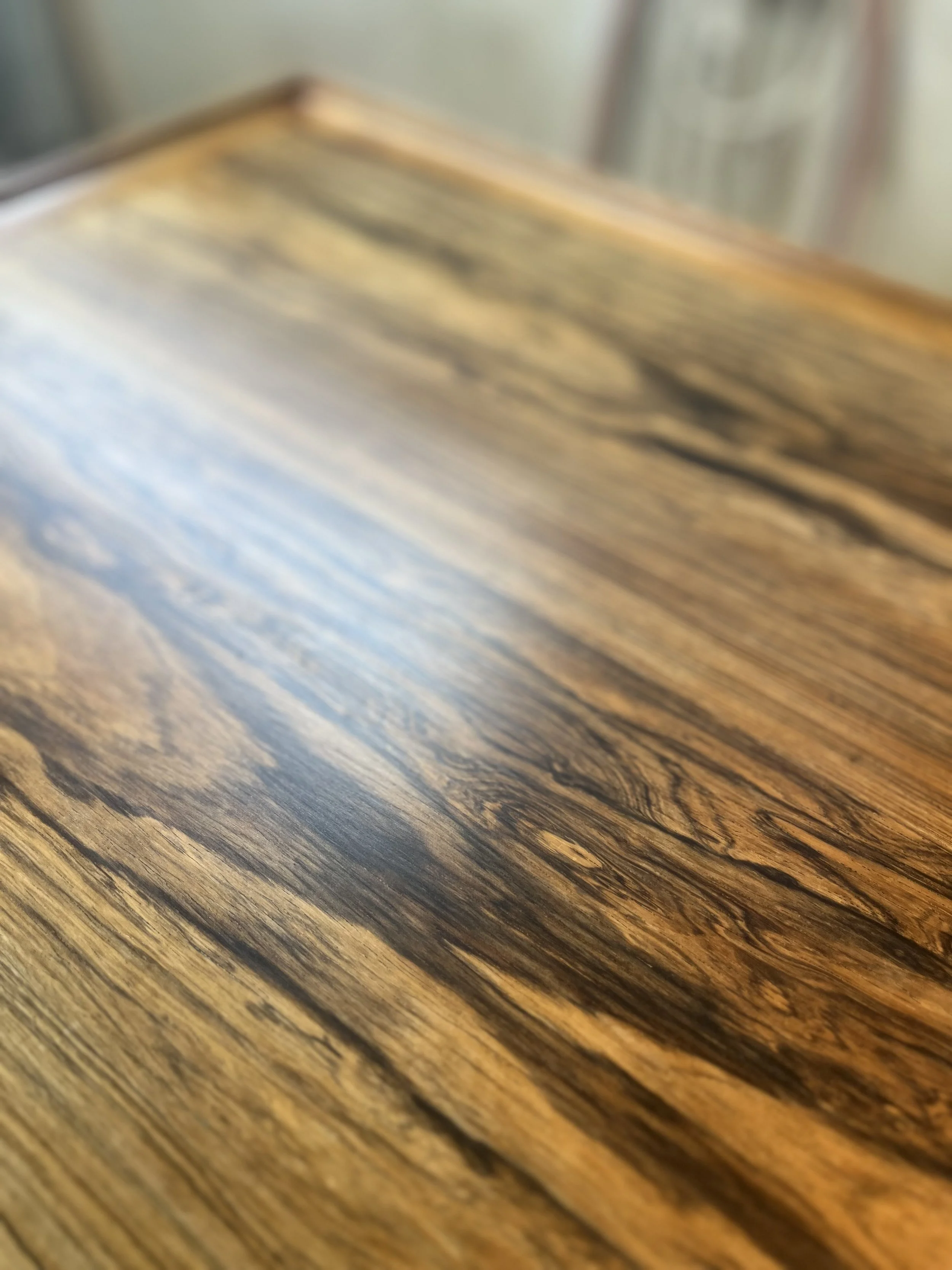 Close-up image of a wooden surface with a polished finish, showcasing natural wood grain patterns and warm brown tones.