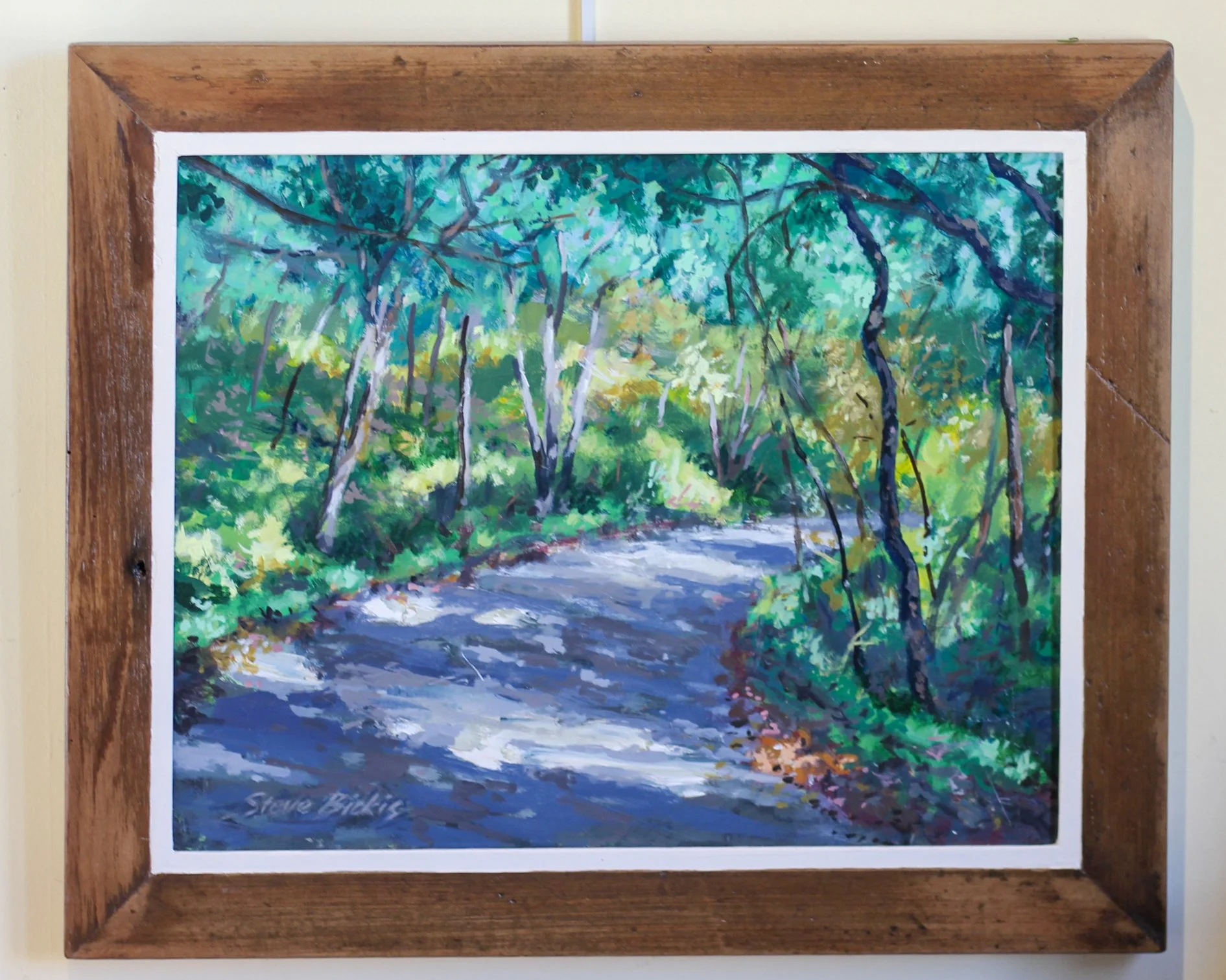 Painting of a wooded trail with trees and green foliage, signed by Steve Biddis
