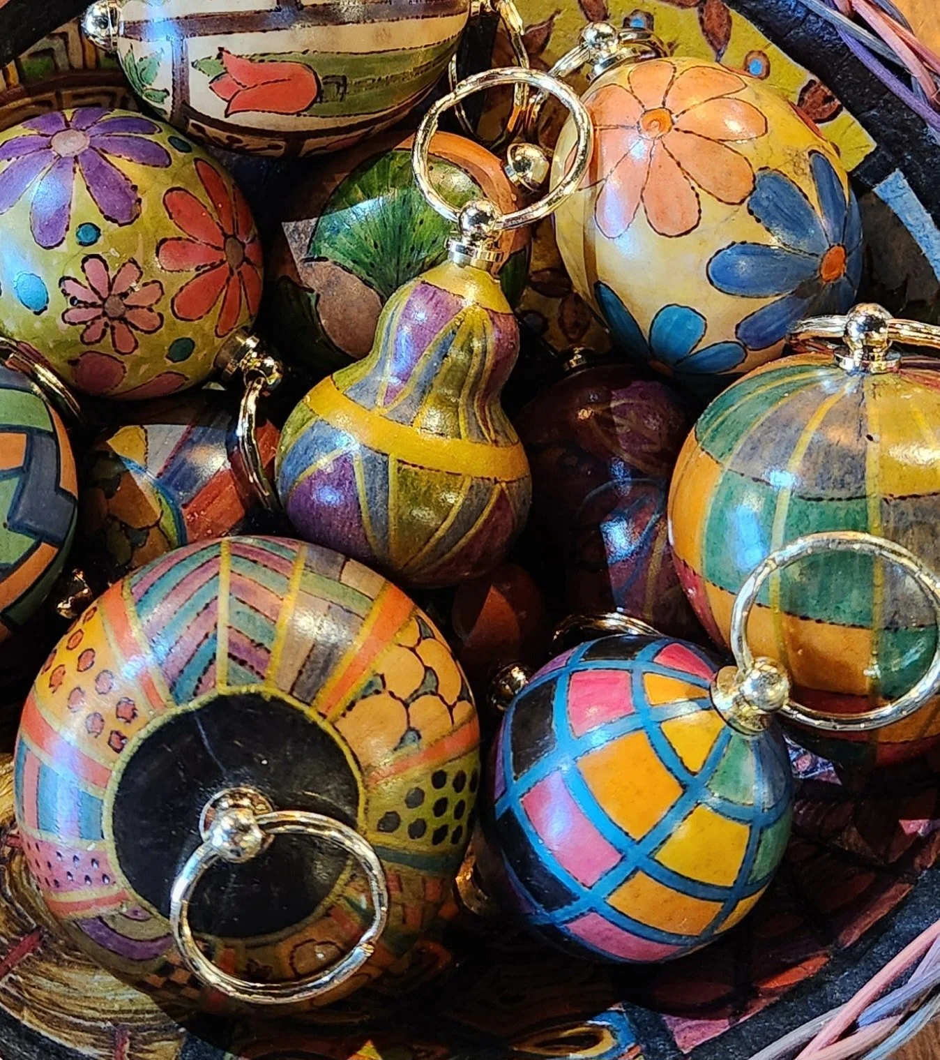Colorful hand-painted glass Christmas ornaments with floral and geometric patterns in a basket.