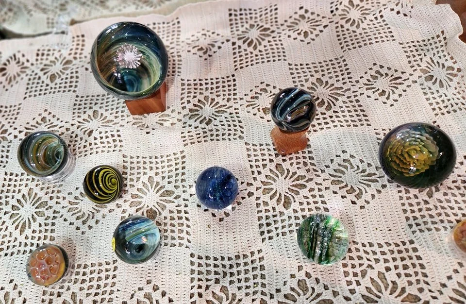 Assorted colorful glass marbles placed on a white lace tablecloth.