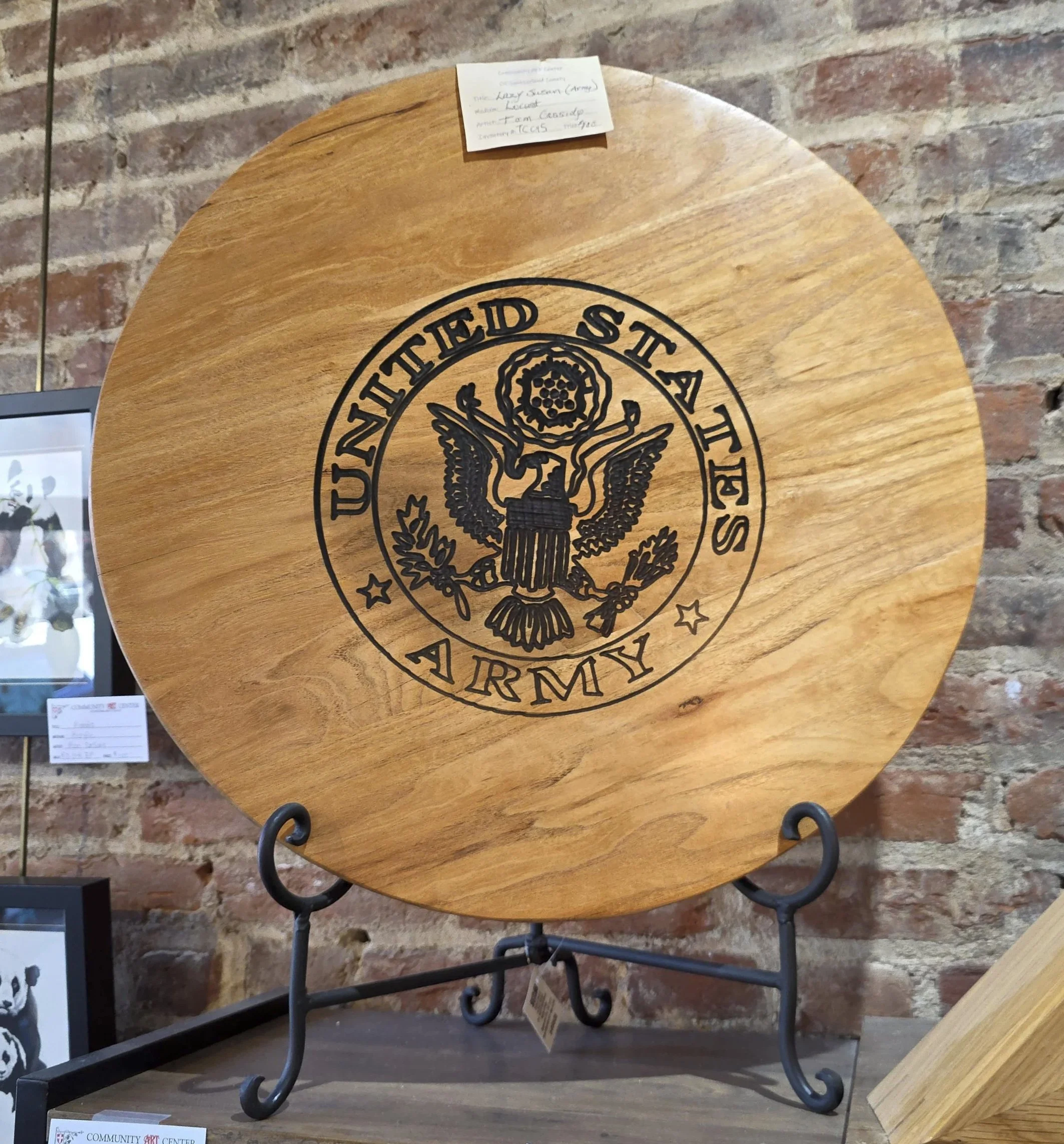 Round wooden plaque with U.S. Army emblem engraved in black created by artisan woodworker Tom Cassidy,  located at the Community Art Center of Switzerland County in Vevay, Indiana