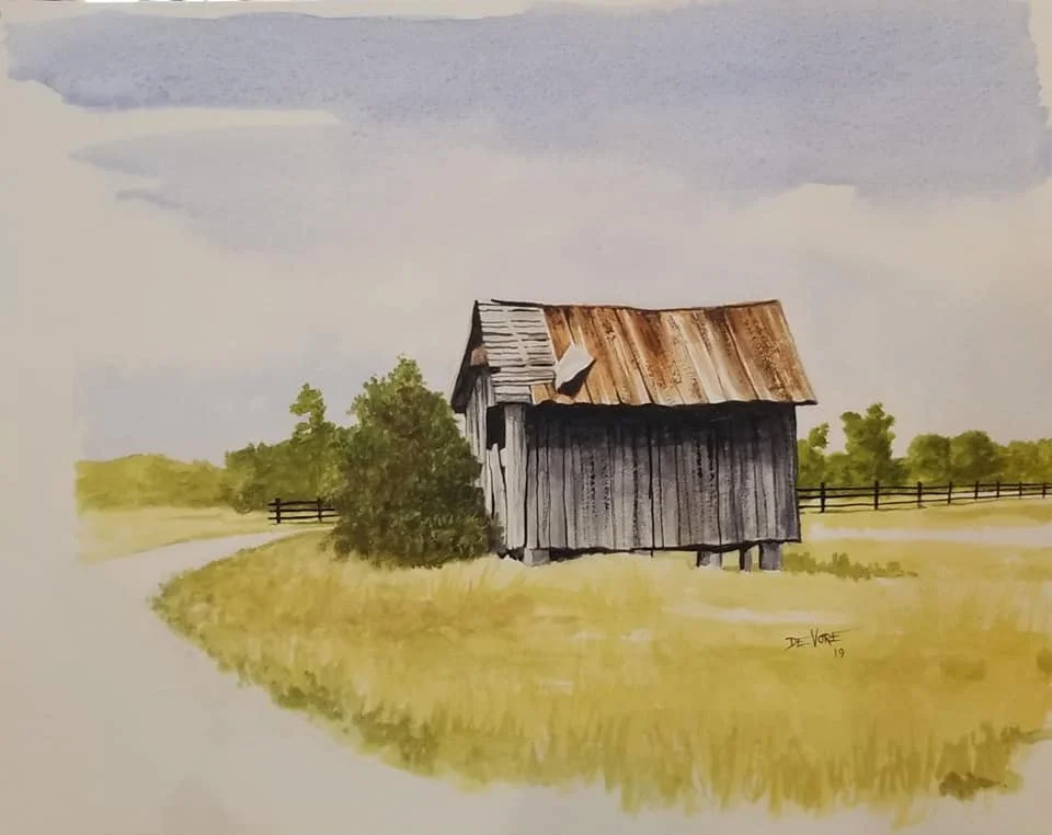 A watercolor painting of an old weathered barn with a rusty roof, surrounded by green grass, bushes, and trees, with a dirt path and fences in the background under a partly cloudy sky.
