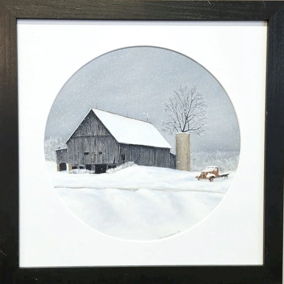 Winter scene of a rural barn with a snow-covered roof, a leafless tree, a silo, and an old truck in the snow, framed and viewed through a circular window.