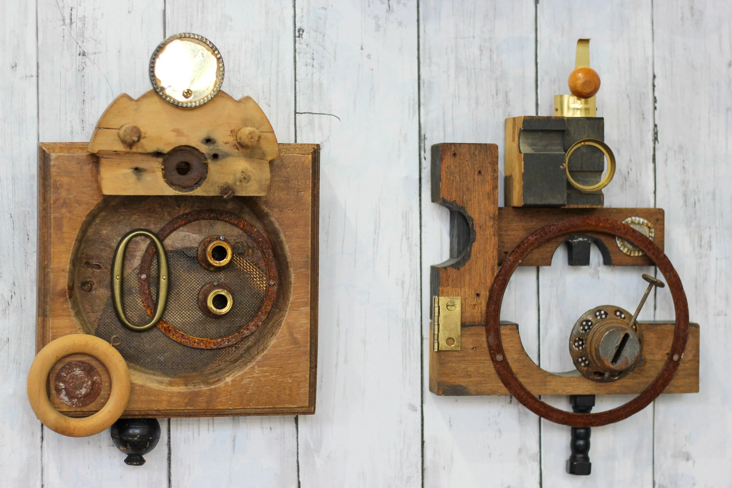 Two vintage wooden mechanical devices with metal and brass components, set against a white weathered wooden background.