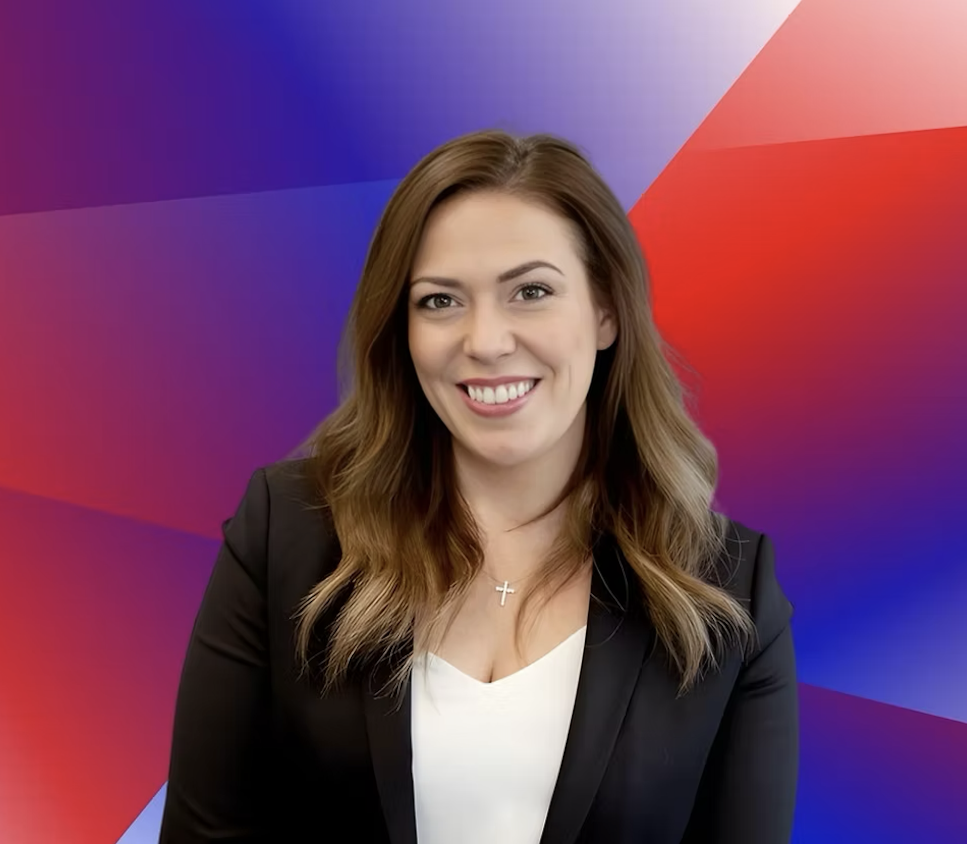 A woman with long, wavy brown hair, wearing a black blazer over a white top, smiling at the camera with a colorful geometric background.