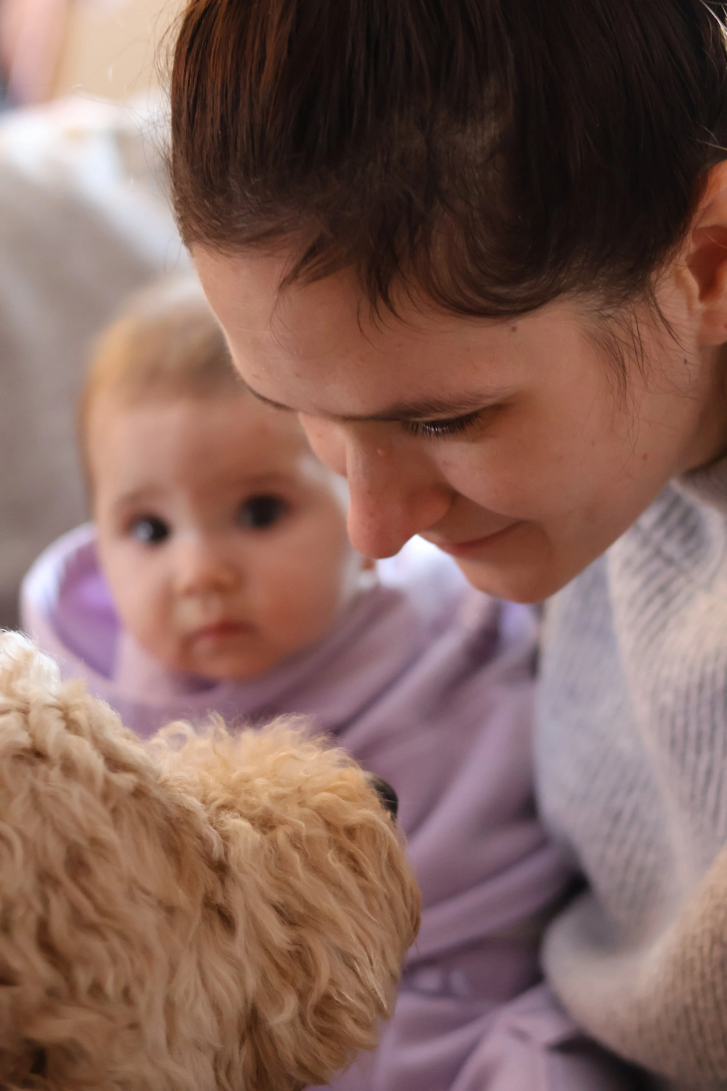 A woman and a young girl looking at a small curly-haired puppy.