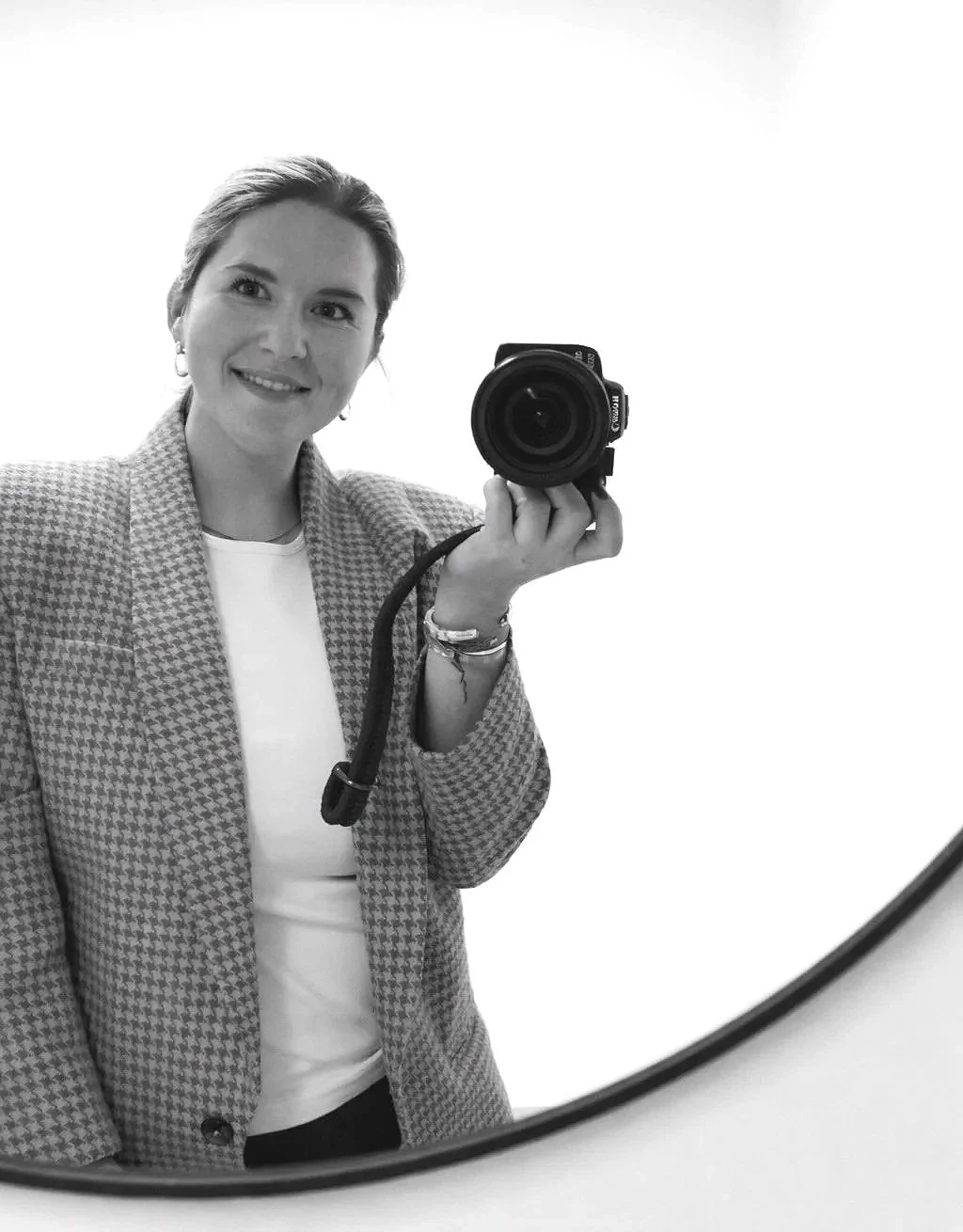 A woman taking a selfie with a camera in front of a mirror in black and white.